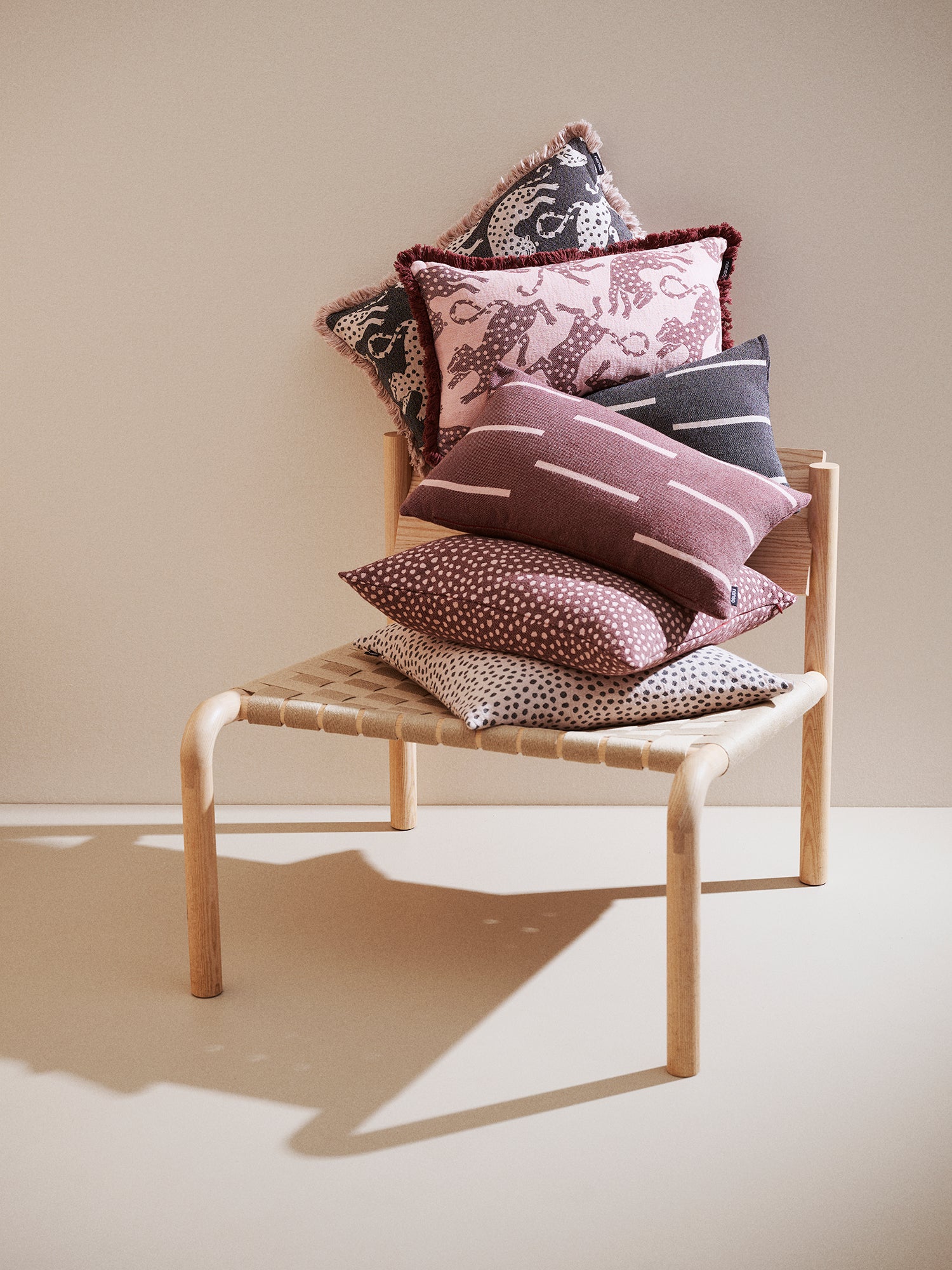 The Jana pillowcase in brown and black pictured with other same colored pillows on a chair.