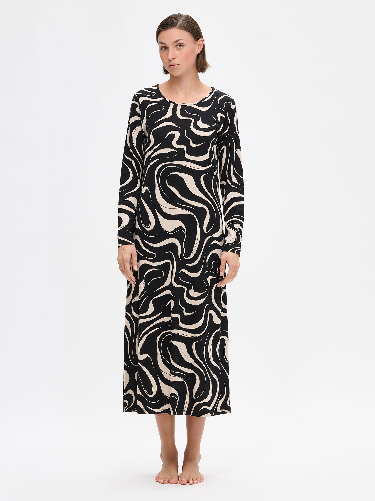 Nanso VESI long-sleeved nightgown black and beige tones with an elegant patterned design. Features a classic round neckline and relaxed fit and soft material for restful nights. On a model from the front.