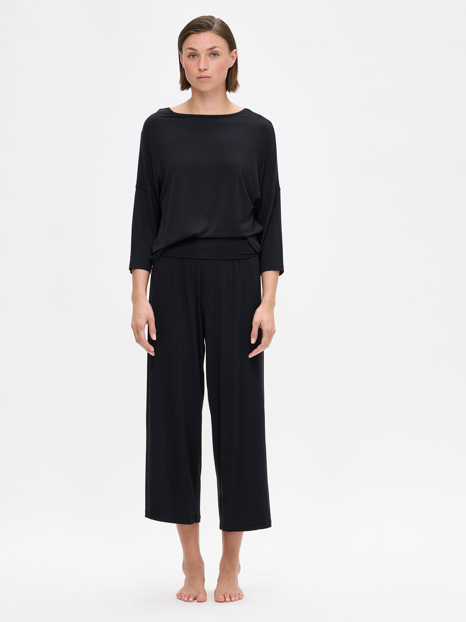 The HENTO 3/4 Sleeve Shirt delivers understated elegance in a luxuriously soft, silk-like fabric. It features gently tapered kimono sleeves and a refined neckline. On a model pictured from the front.
