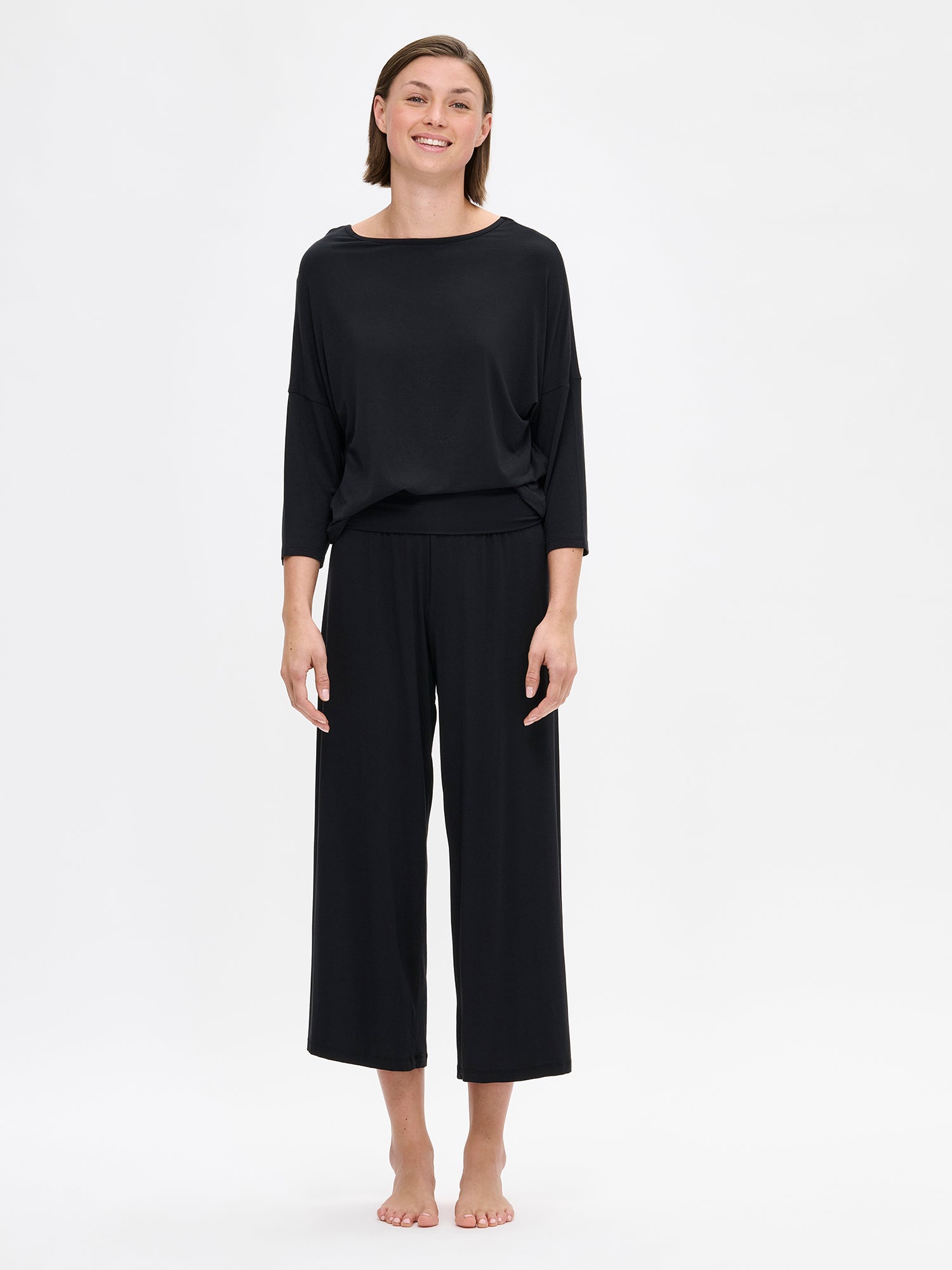 The HENTO 3/4 Sleeve Shirt delivers understated elegance in a luxuriously soft, silk-like fabric. It features gently tapered kimono sleeves and a refined neckline. On a model pictured from the front.