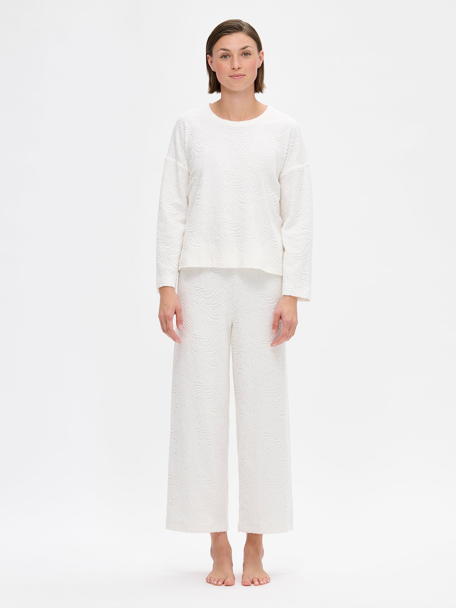 Nanso Väre relaxed-fit lounge pants with a beautifully textured fabric offer full-length coverage with an elastic waistband that provides a comfortable, secure fit throughout the day. On a model pictured from the front.