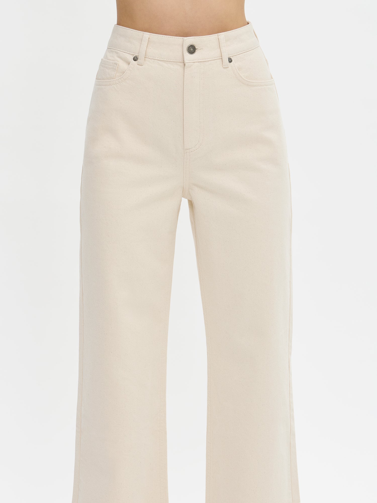 Nanso women’s off white Levee jeans with a high waist and wide flared legs, on a model from the front, close-up.