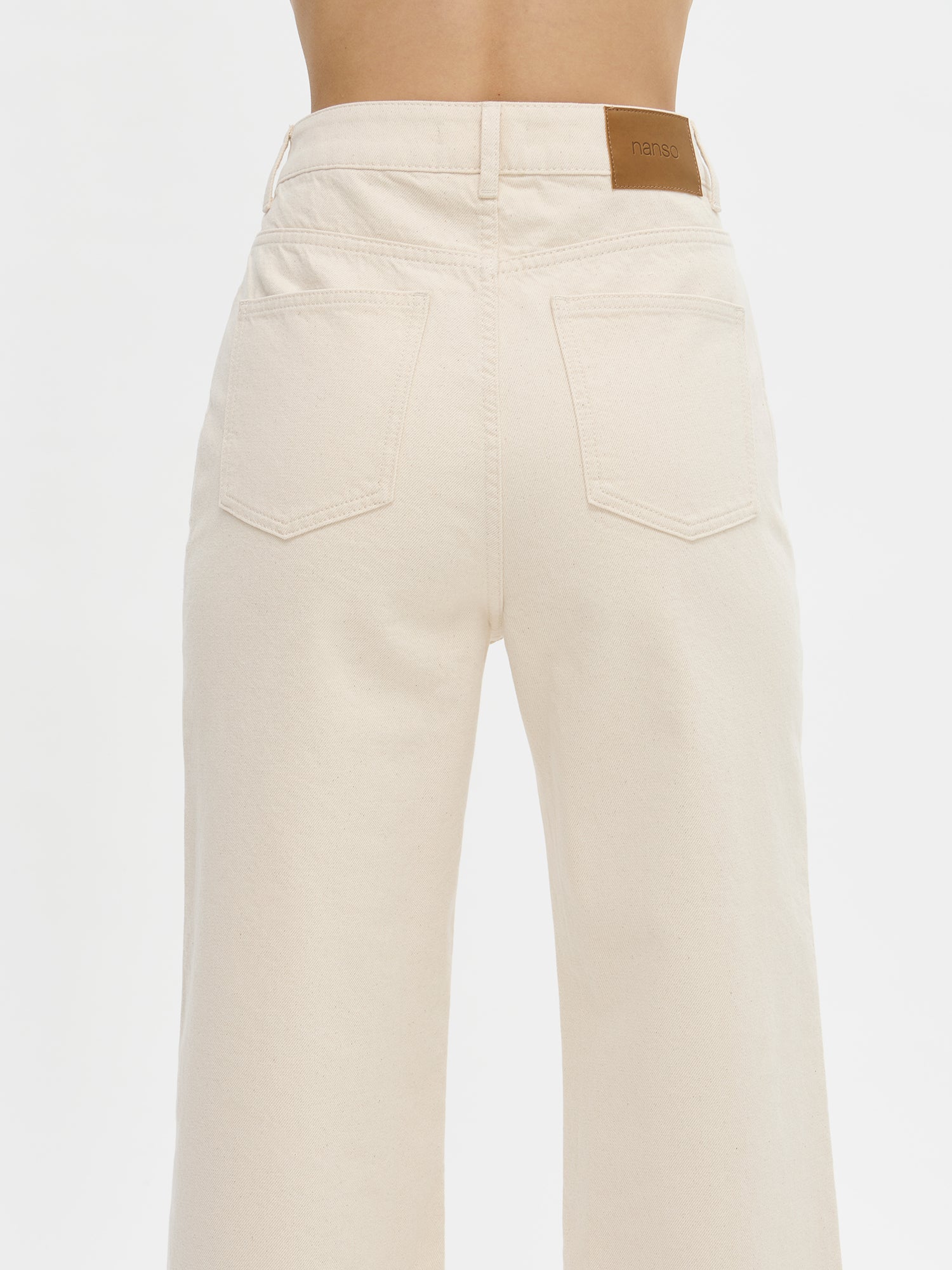 Nanso women’s off white Levee jeans with a high waist and wide flared legs, on a model from the back, close-up.