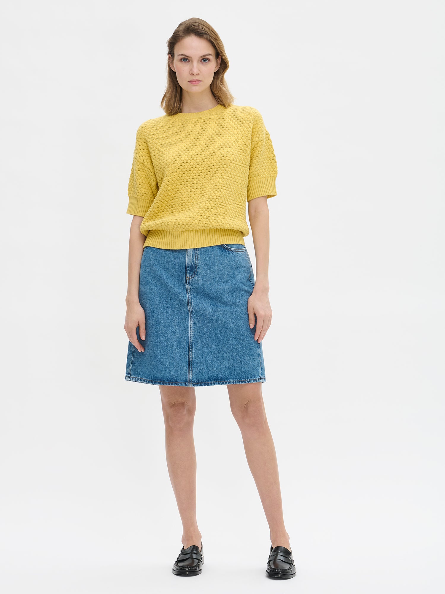 Nanso women's Kumpu versatile short-sleeved knit sweater in yellow on a model with a denim skirt.