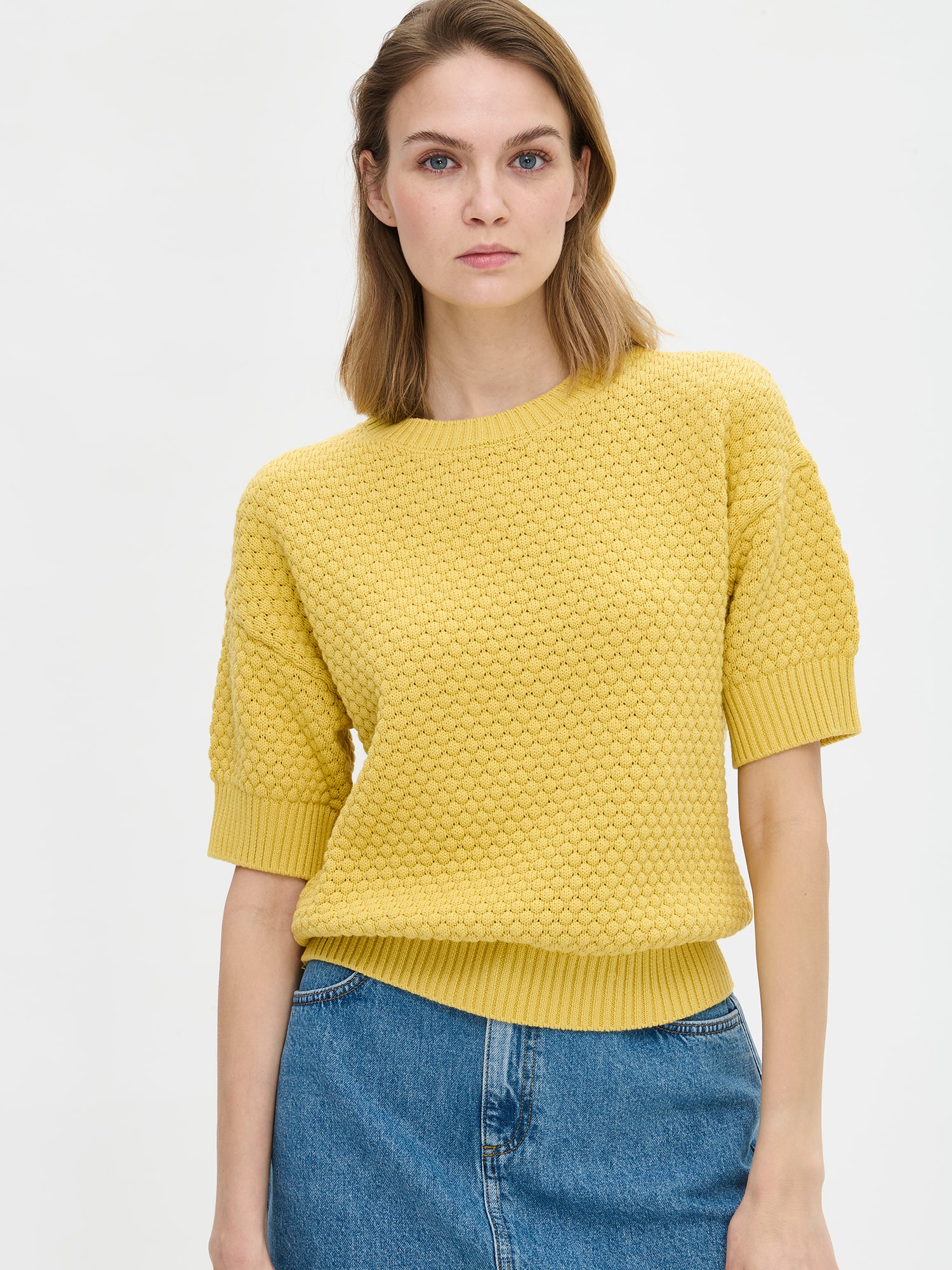Nanso women's Kumpu versatile short-sleeved knit sweater in yellow on a model with a denim skirt.