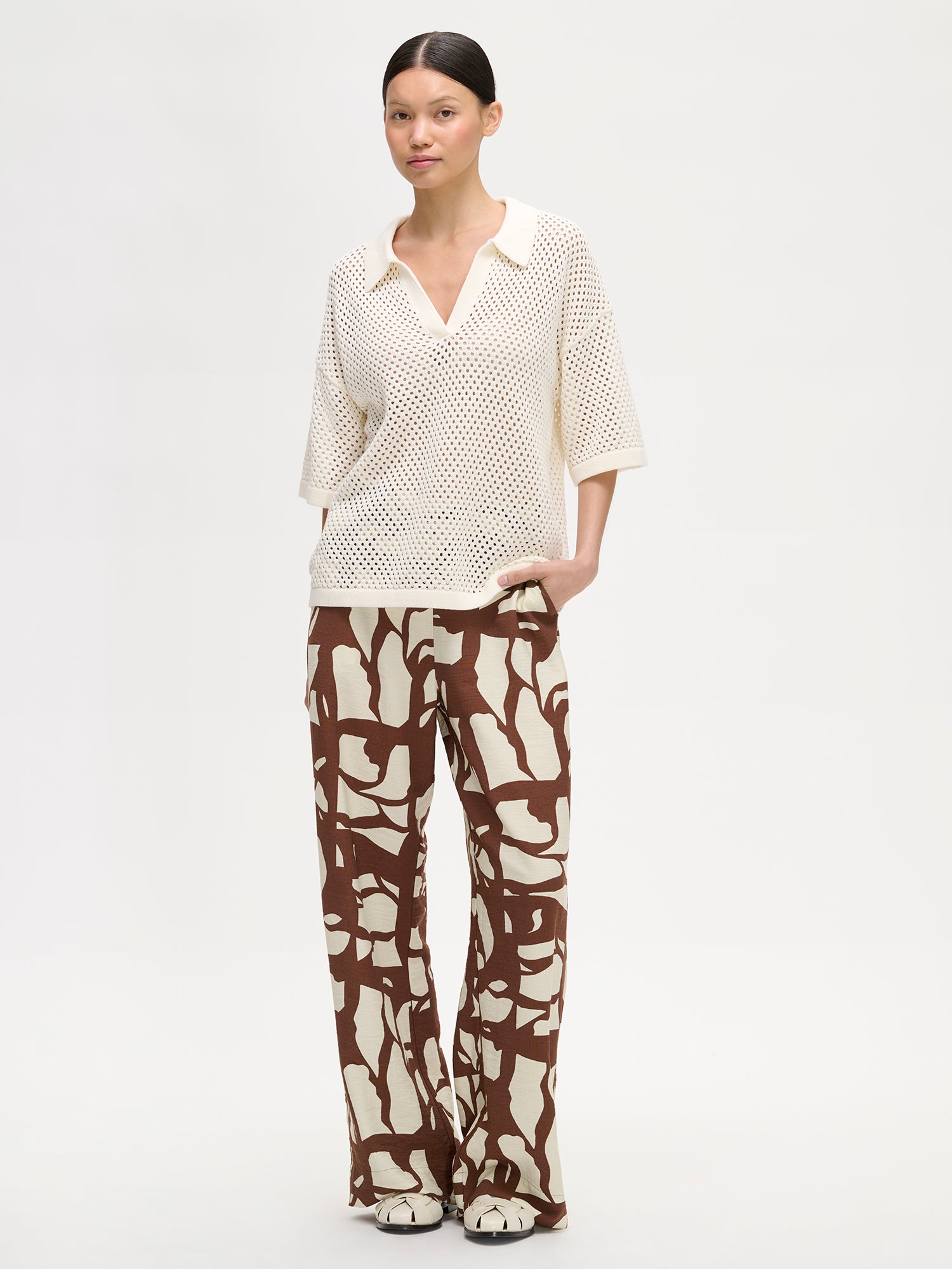 Nanso women's AURE natural white openwork knit sweater on a model with patterned trousers in brown and white.