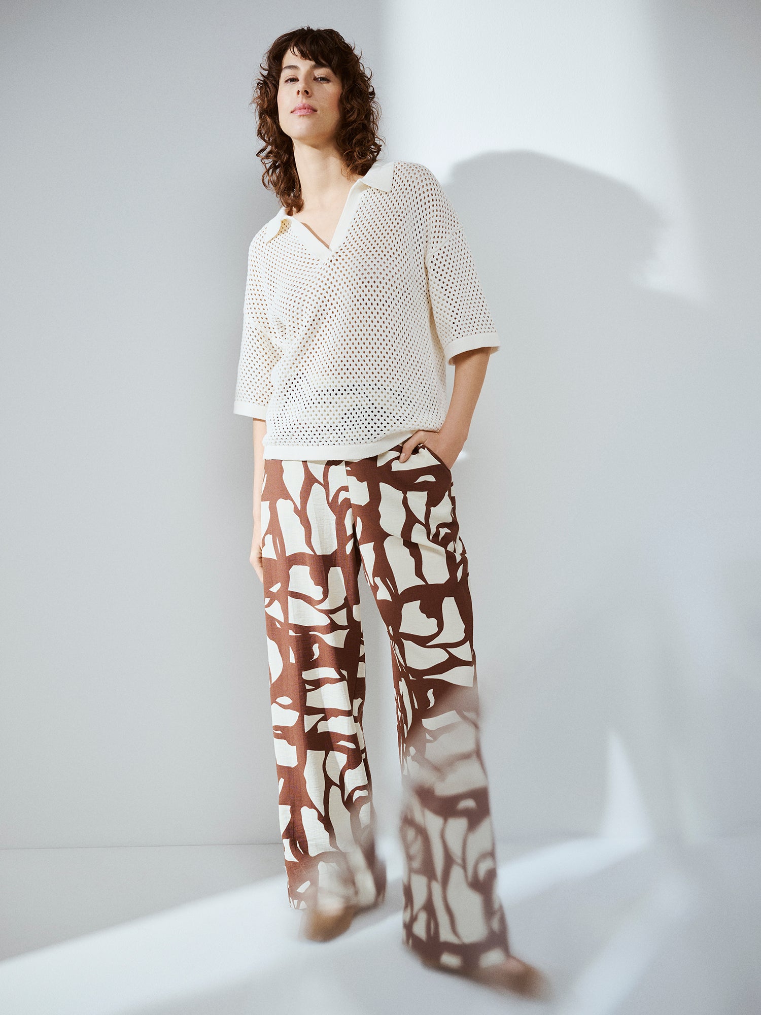Nanso women's AURE natural white openwork knit sweater on a model with patterned trousers in brown and white.