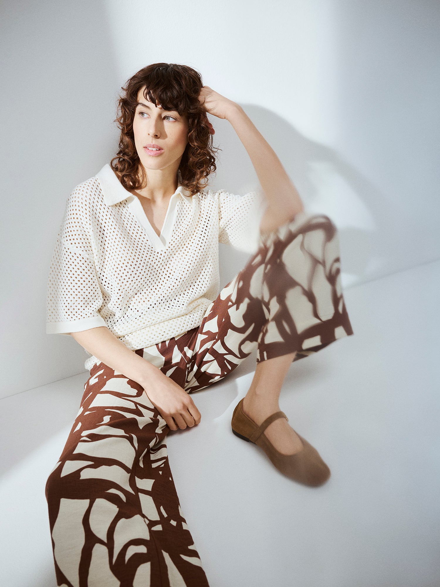 Nanso women's AURE natural white openwork knit sweater on a model with patterned trousers in brown and white.