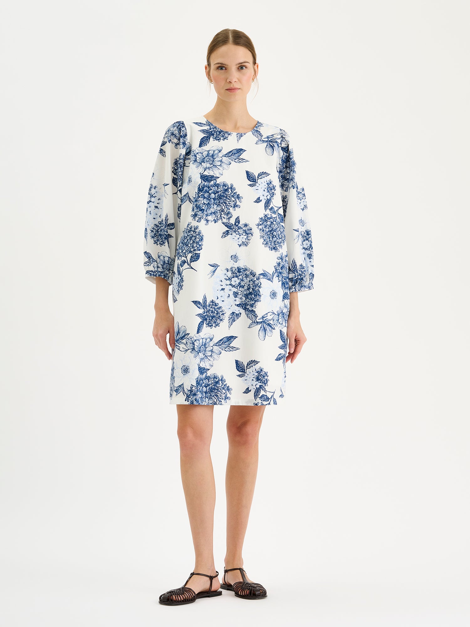 Nanso Palatsi Dress in a striking blue and white floral pattern on a model with sandals
