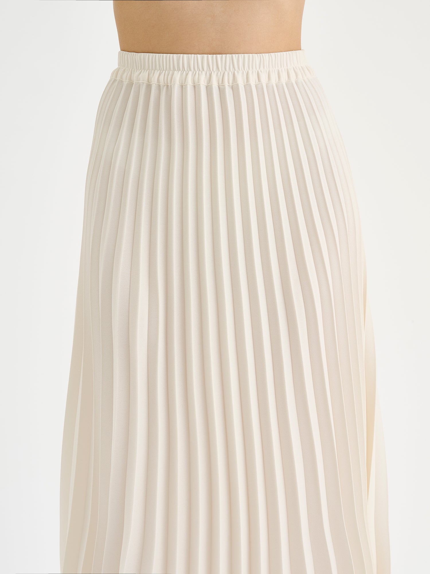 ARIEL pleated midi-length skirt in a fresh white shade on a model, close-up.