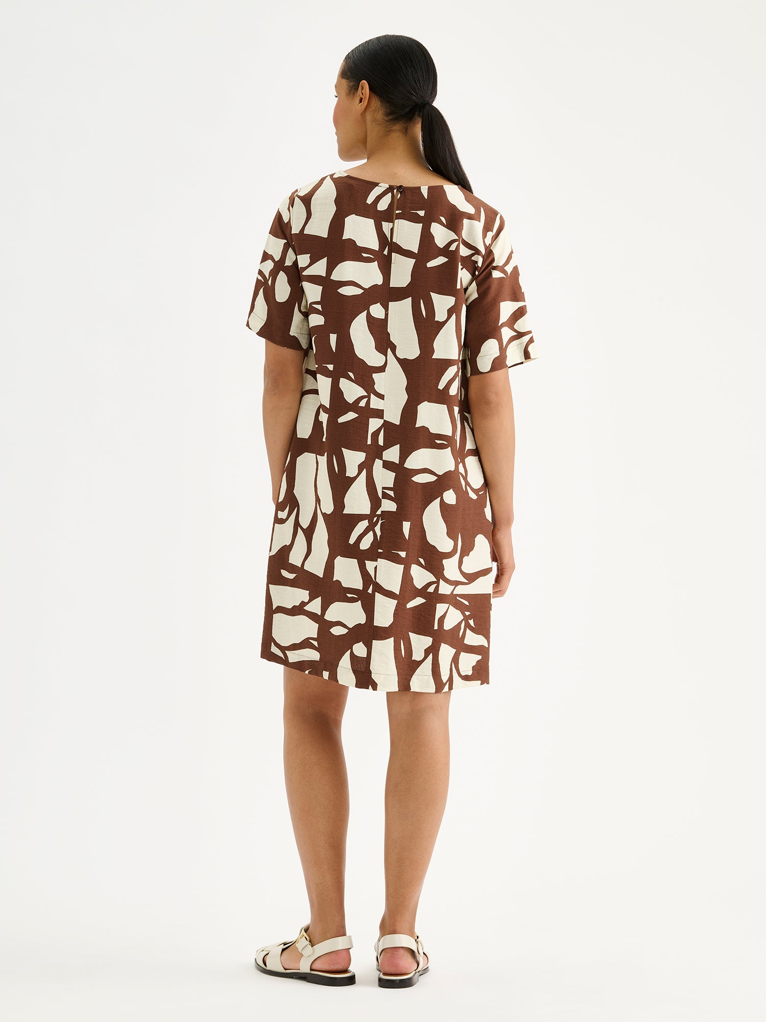 Nanso women's relaxed, straight-cut Palsta dress with timeless appeal and a stylish print in rich brown shade on a model pictured from the backside