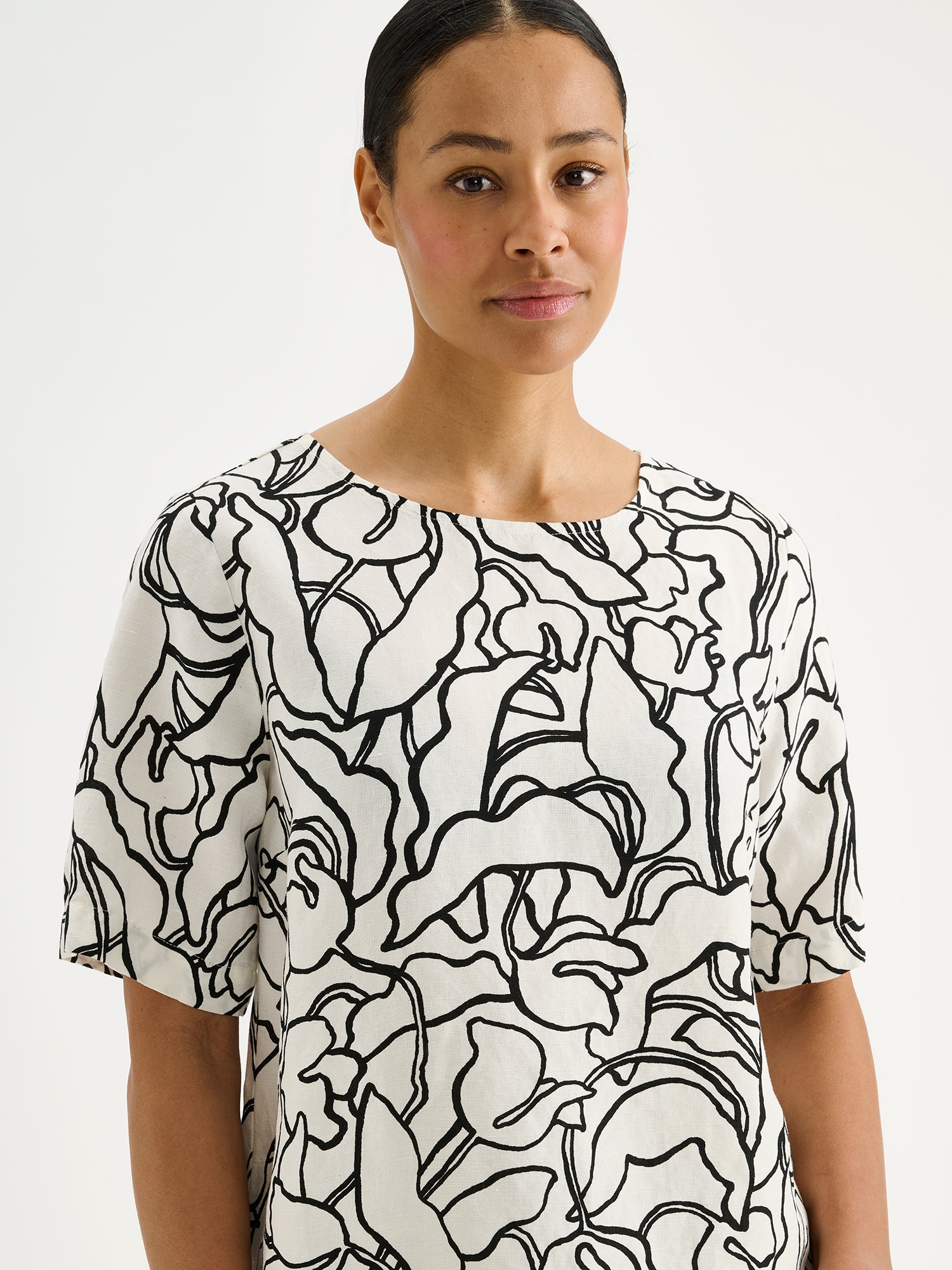 Nanso women's stylish and wonderfully relaxed IIRIS blouse featuring half-length sleeves and an elegant black and white floral pattern on a model close-up.