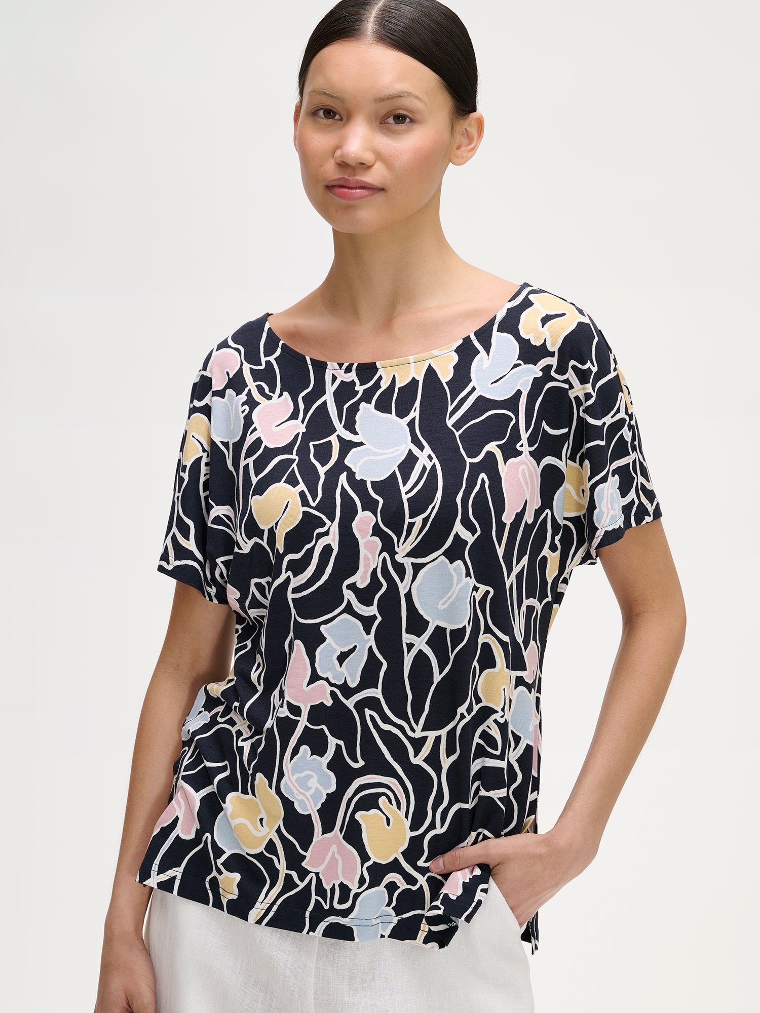 Nanso IIRIS floral Jersey Blouse on a model with white linen trousers, close-up