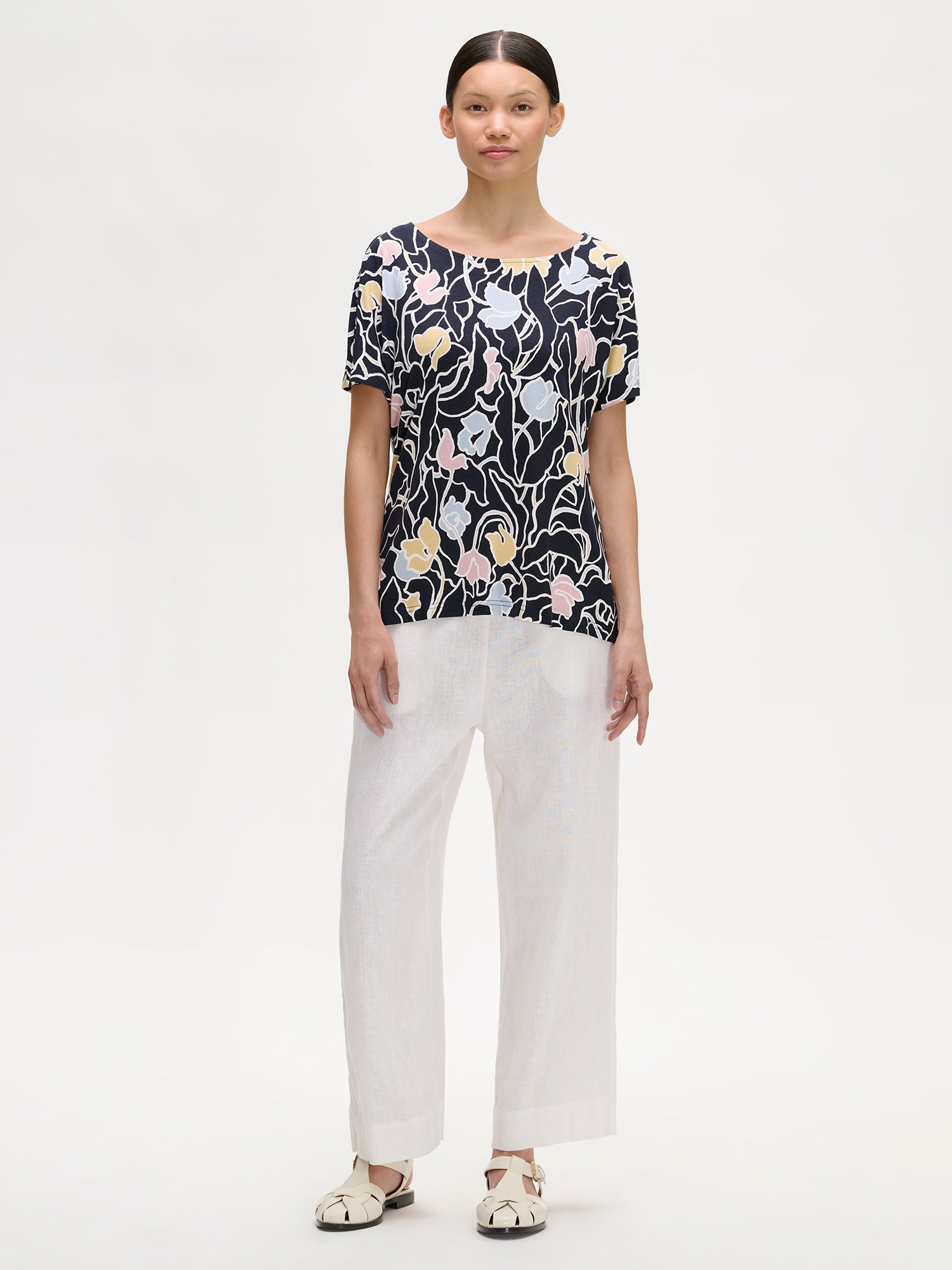 Nanso IIRIS floral Jersey Blouse on a model with white linen trousers.