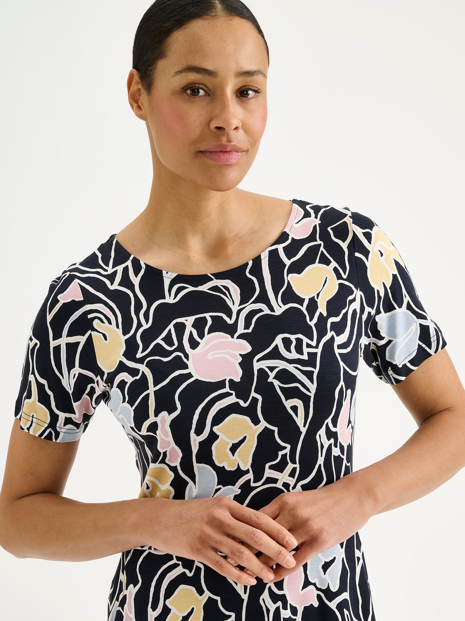 Nanso Iiris dress features a stylish floral pattern on soft, flowing fabric. Pictured on a model, close-up.