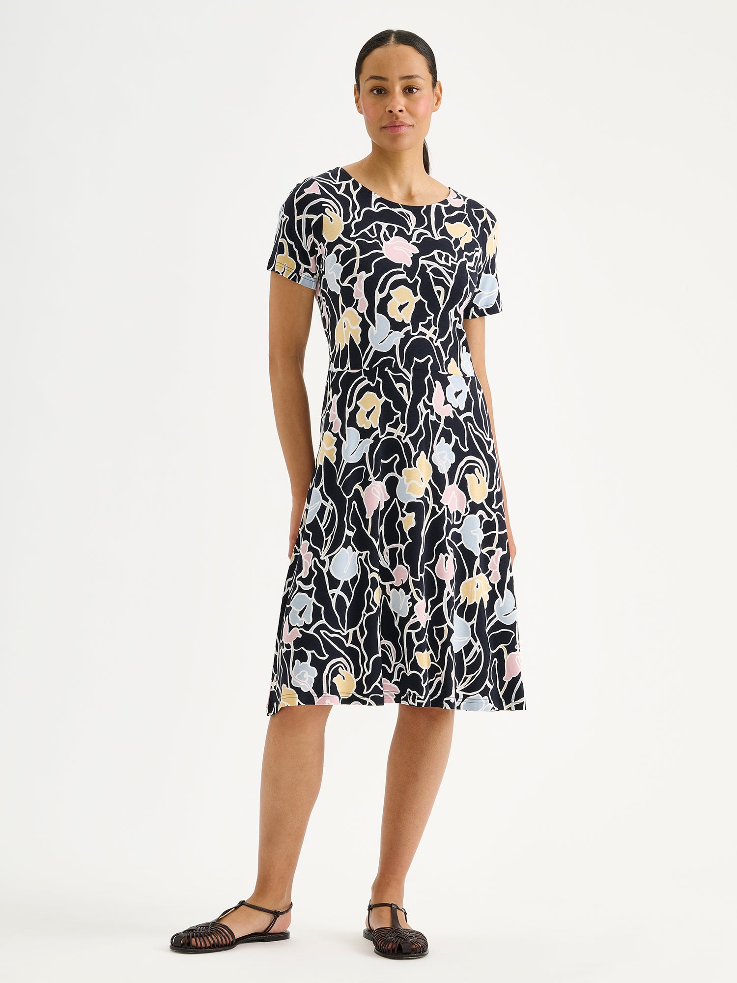 Nanso Iiris dress features a stylish floral pattern on soft, flowing fabric. Pictured on a model