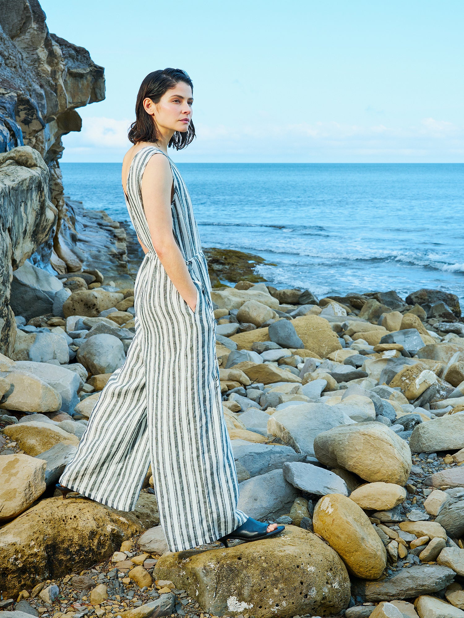 The elegant REGATTA linen jumpsuit with vertical stripes and beautiful cut on a model in a beach scenery.