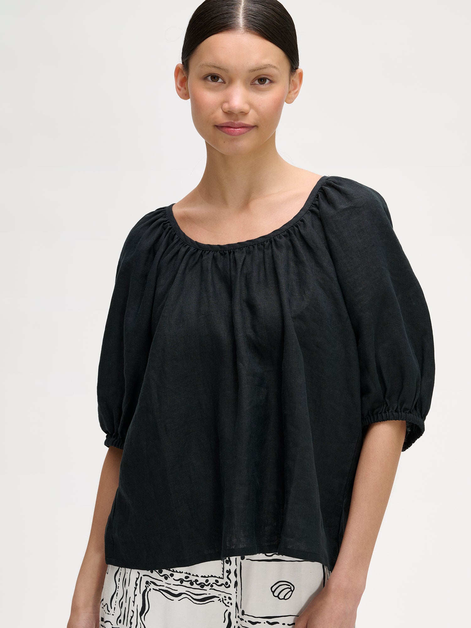 Nanso women's Donna linen blouse in black, on a model with wide patterned trousers, close-up.
