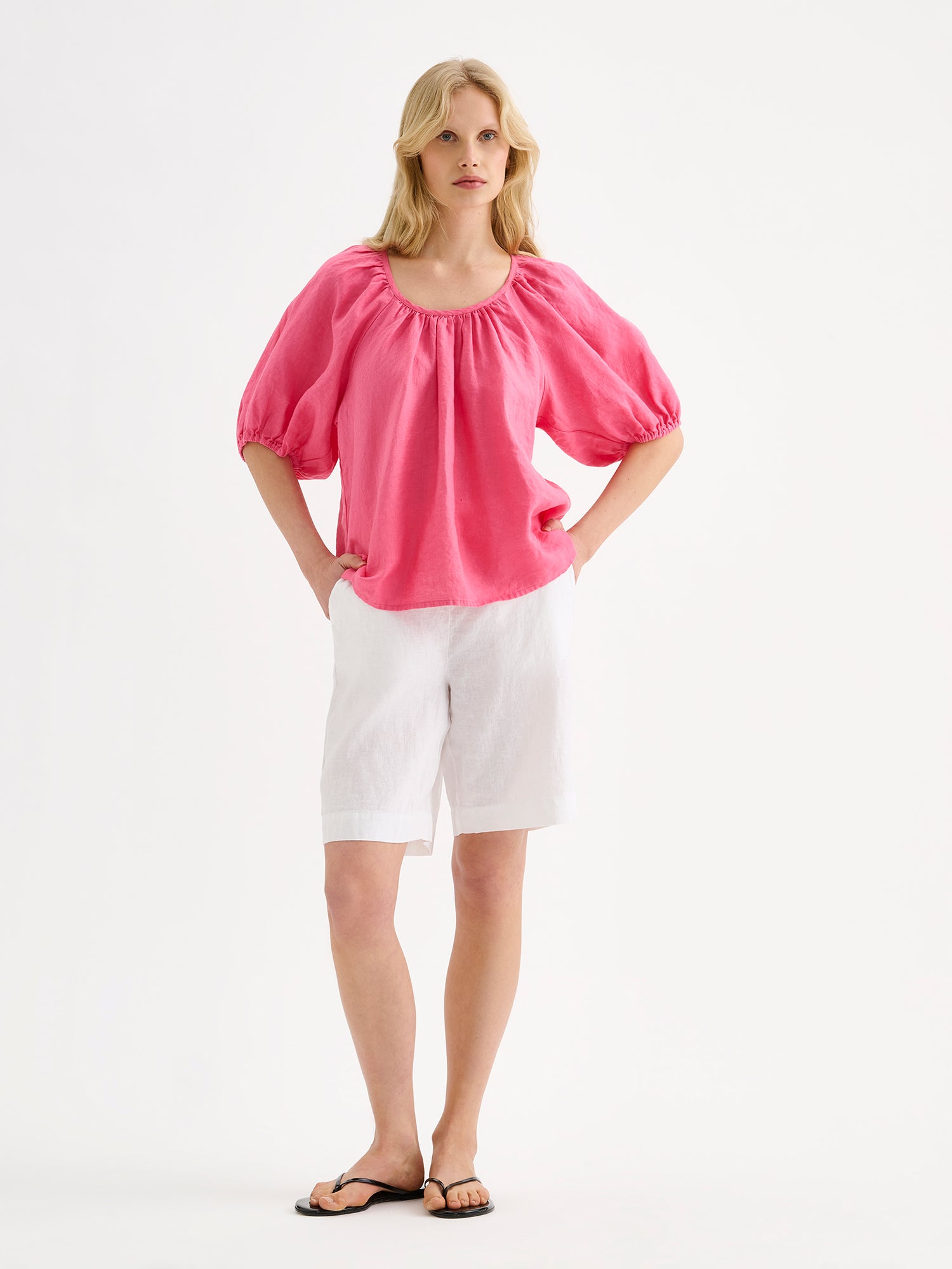 Nanso women's Donna linen blouse in a delicious pink shade on amodel with white shorts and sandals