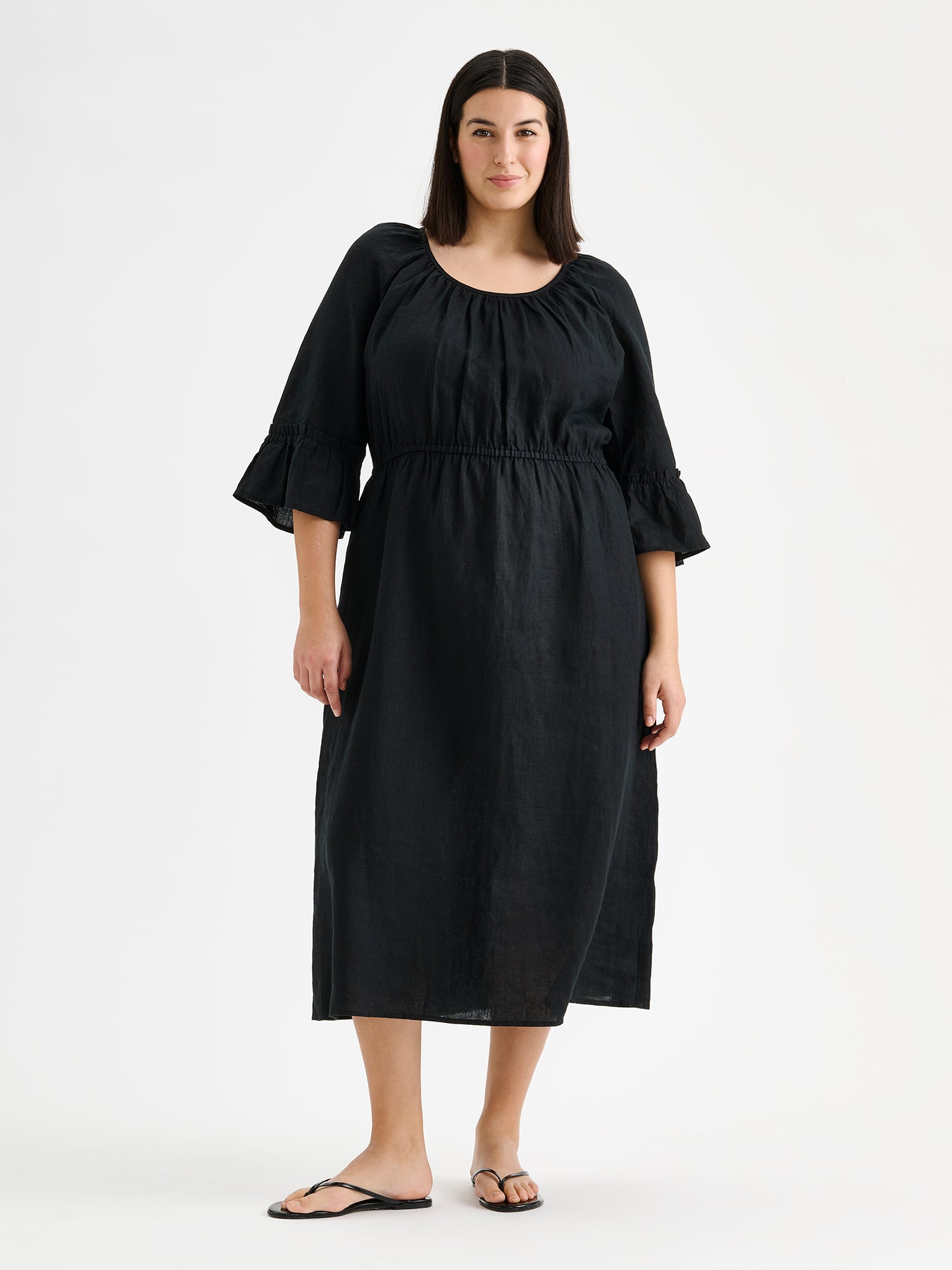Nanso women's black  Donna midi linen dress combines effortless elegance with feminine details. This airy midi-length style features an open, softly gathered back neckline with a striking self-tie bow. Pictured on a model with black sandals.
