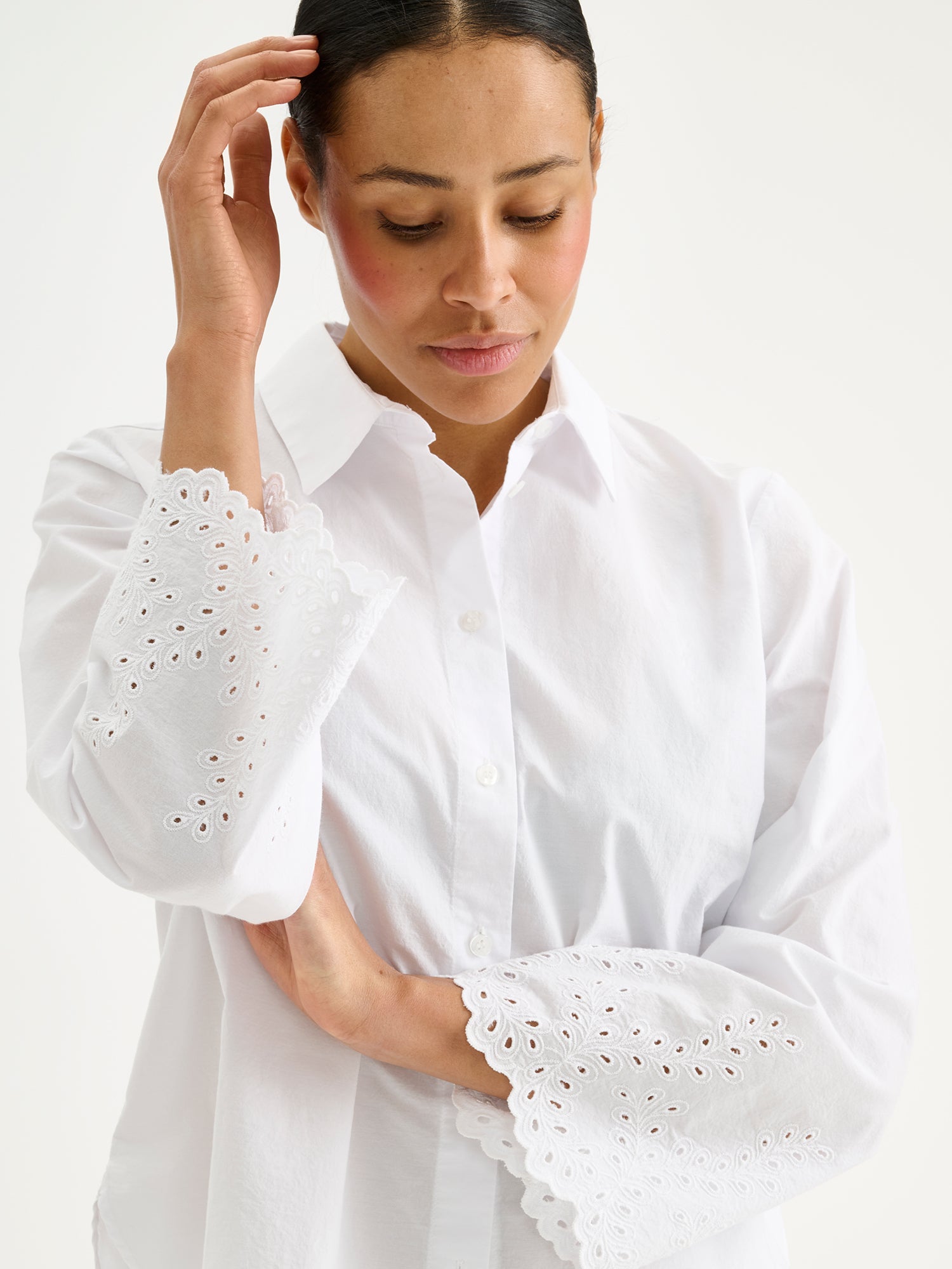 Nanso women's fresh white Sevilla shirt with airy, relaxed sleeves and delicate lace-trimmed edges, on a model, close-up.