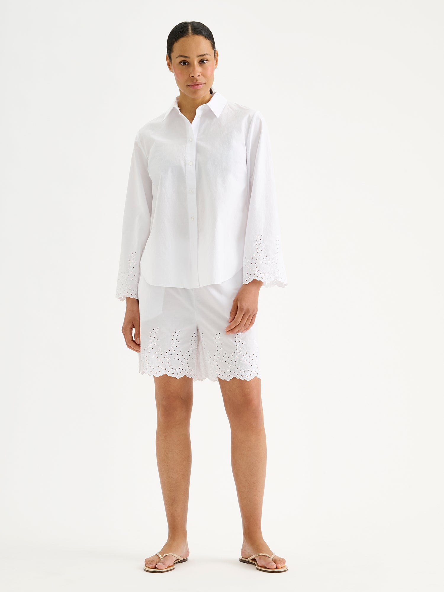 Nanso women's fresh white Sevilla shirt with airy, relaxed sleeves and delicate lace-trimmed edges, on a model with matching shorts.