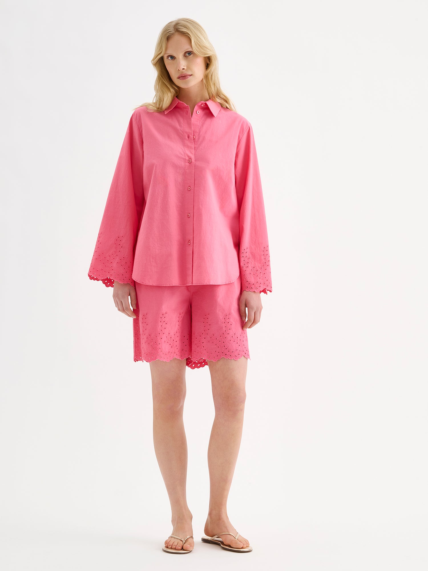 Nanso women's radiant pink Sevilla shirt with airy, relaxed sleeves and delicate lace-trimmed edges on a model with matching shorts.