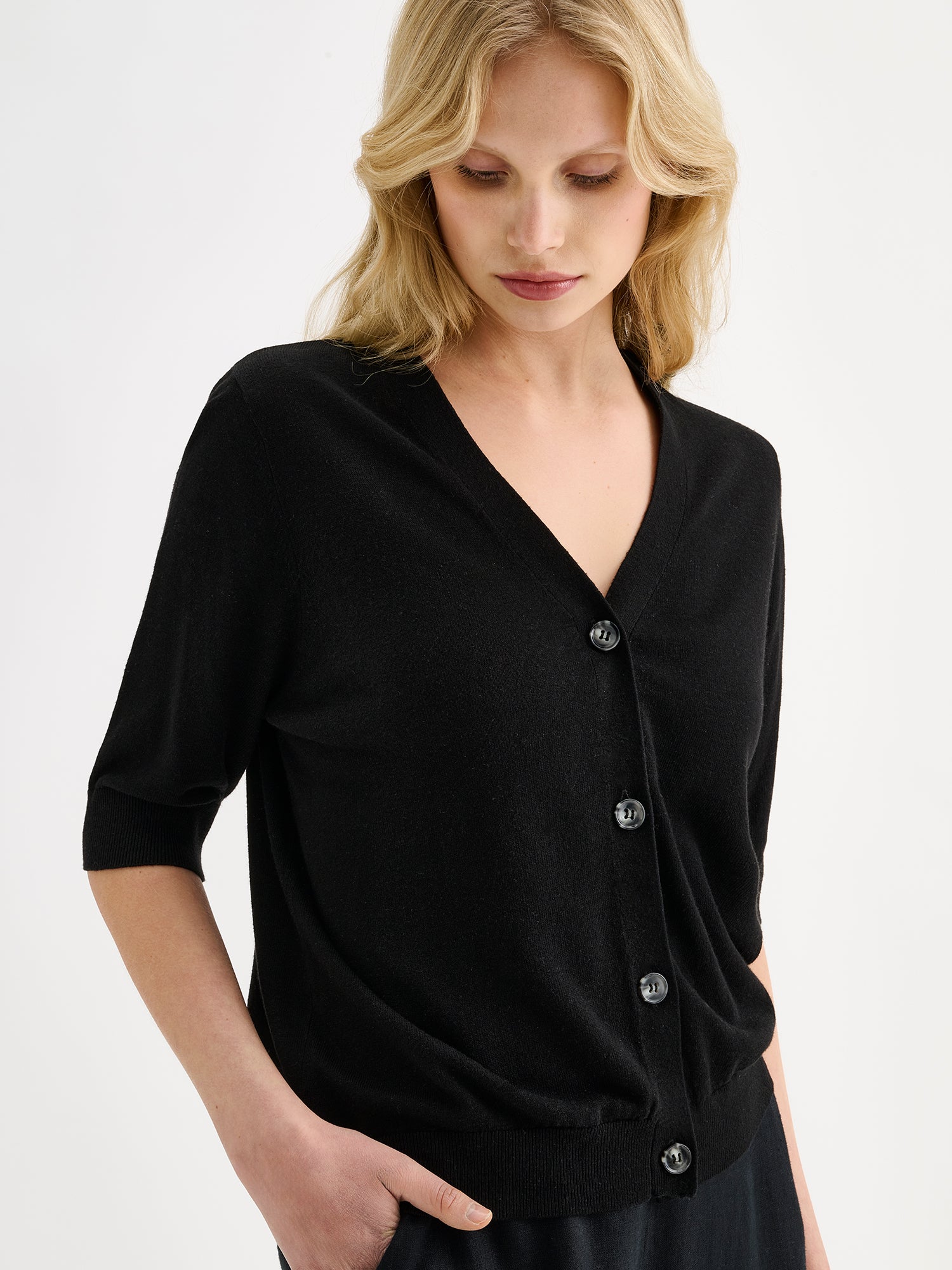 Nanso women's light pink half-sleeve linen blend Karina knit cardigan on a model with black trousers, close-up.