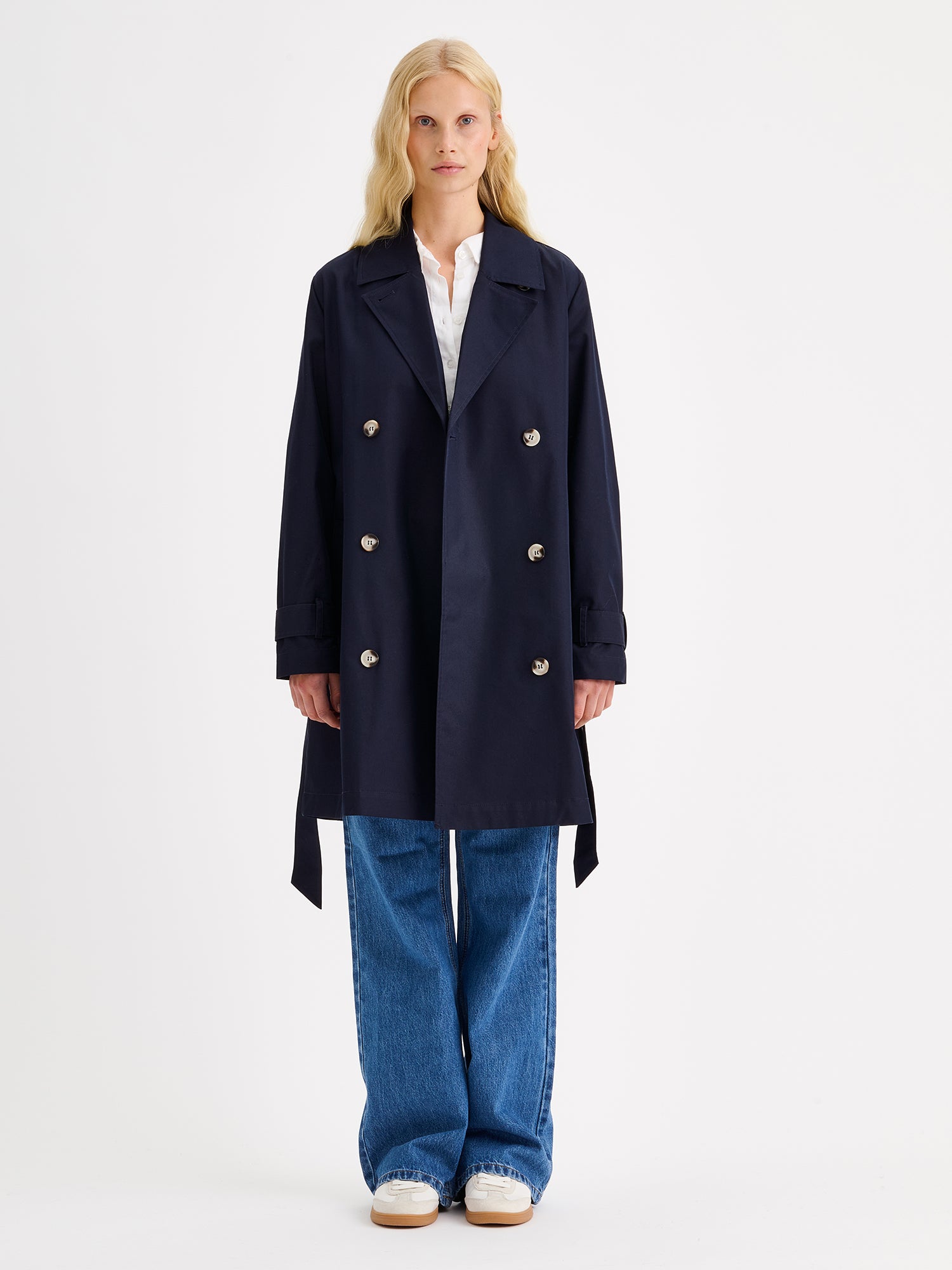 Nanso women's timeless midi trench coat in dark blue on a model with jeans