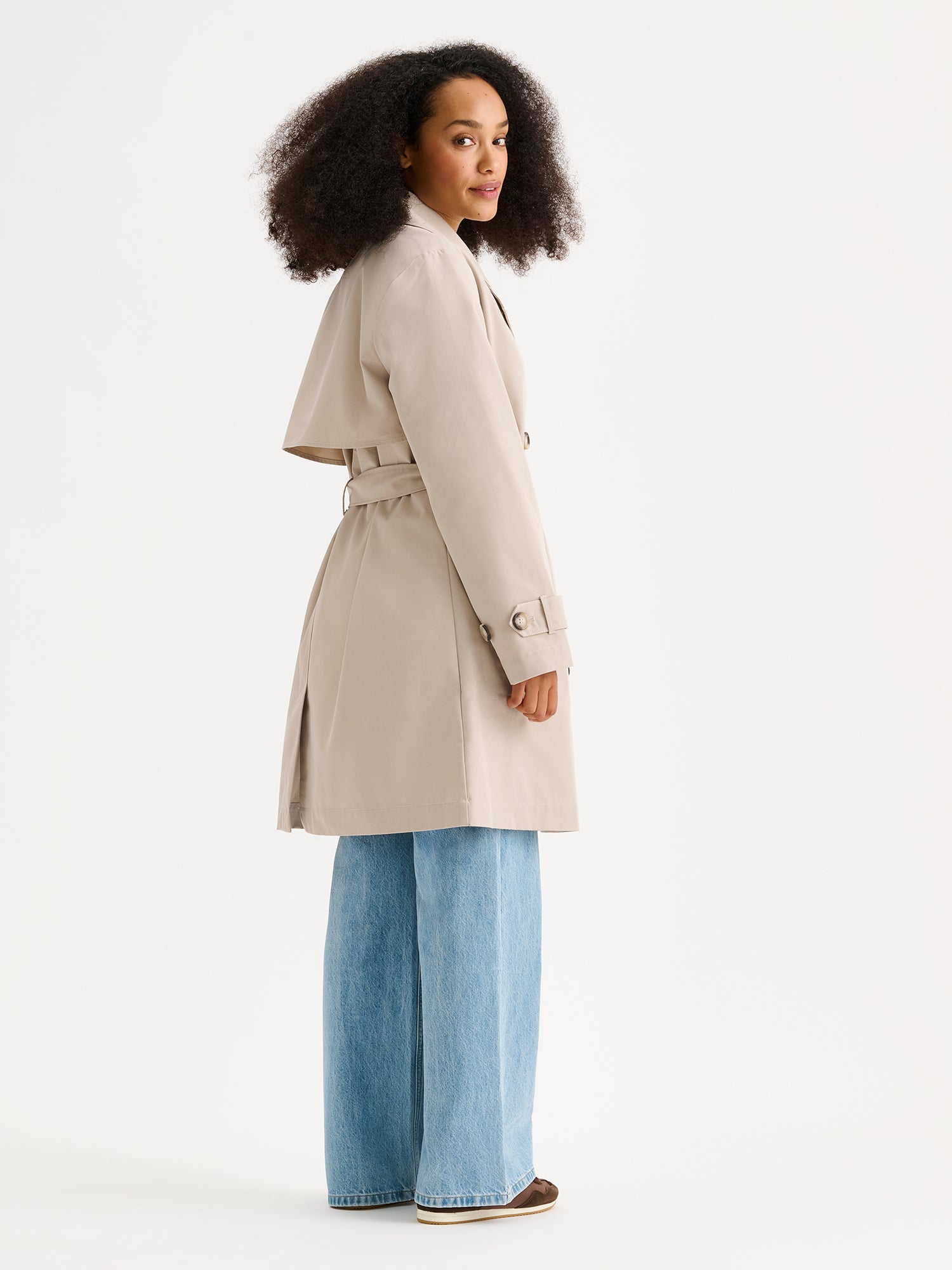 Nanso women's timeless midi trench coat in beige on a model with jeans from the backside