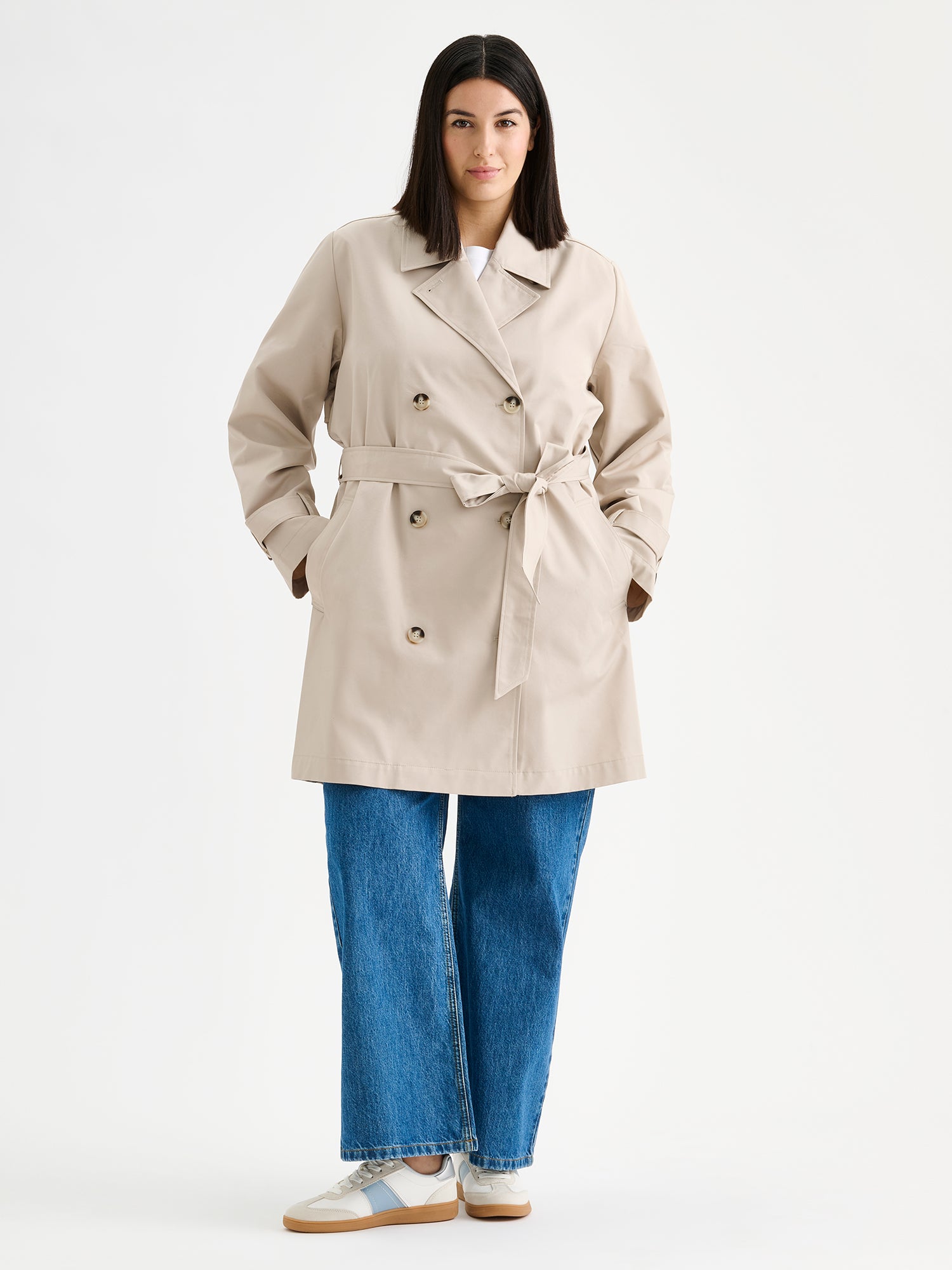Nanso women's timeless midi trench coat in beige on a model with jeans.