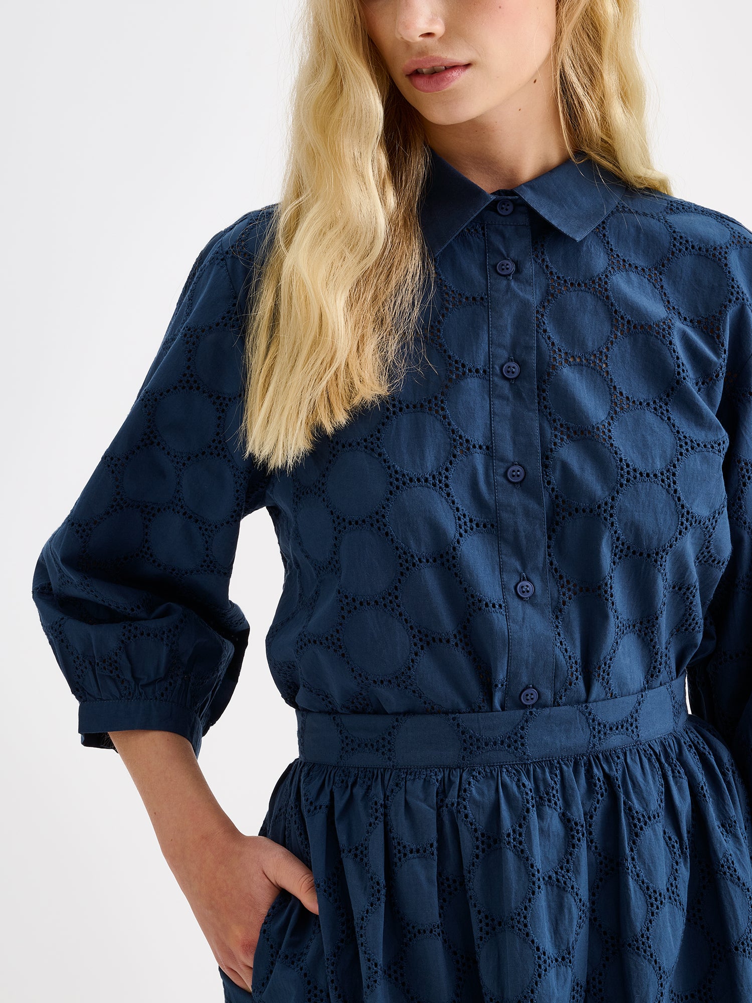 nanso women's stylish dark blue Siiri blouse for women, featuring beautiful embroidered fabric, classic collar, buttons and 3/4 sleeves, on a model with a matching skirt.