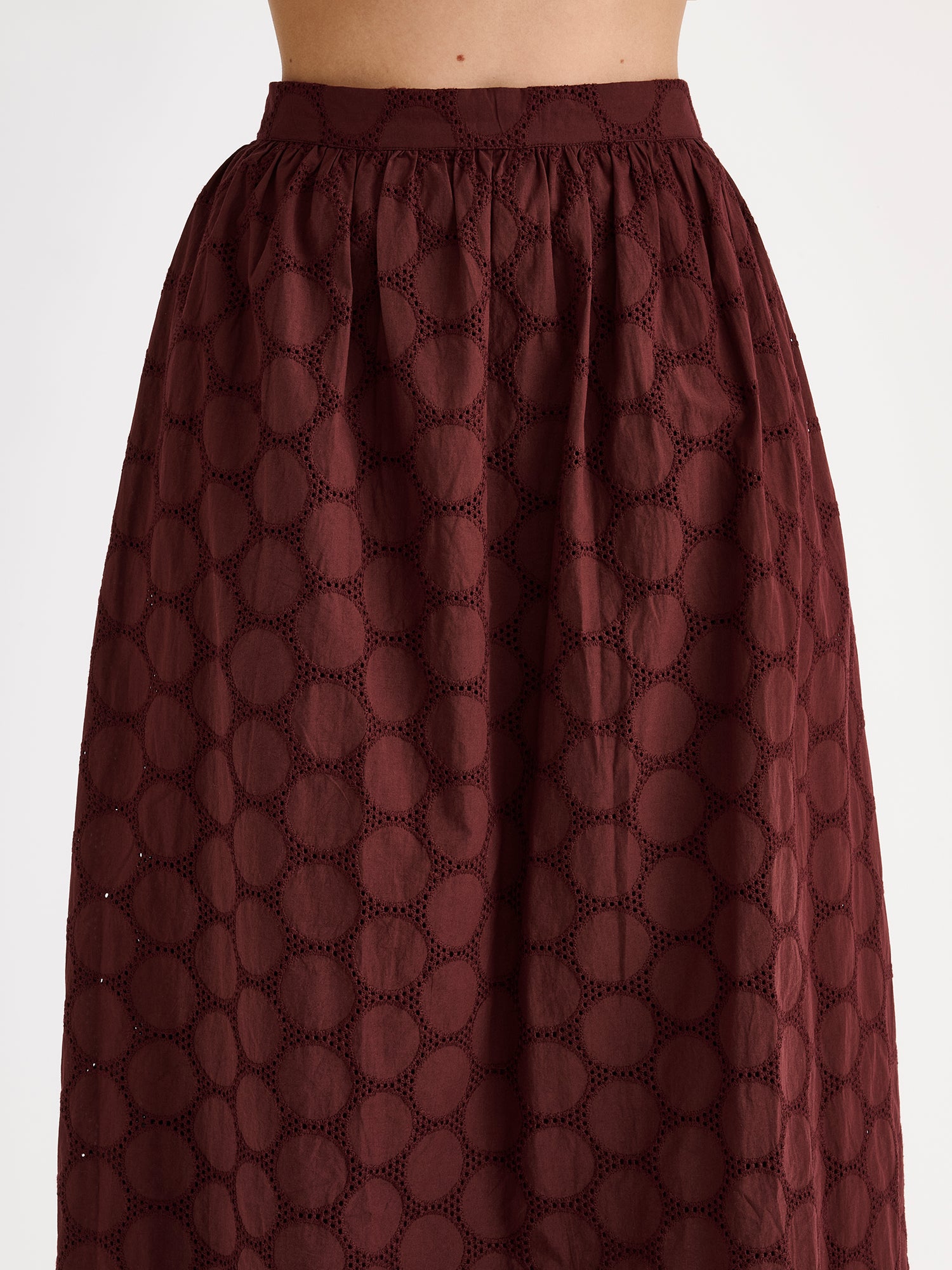 Nanso women's dark brown Siiri midi skirt, featuring a delicate lace-like woven cotton fabric with beautiful texture, pockets and a zip, on a model, close-up.