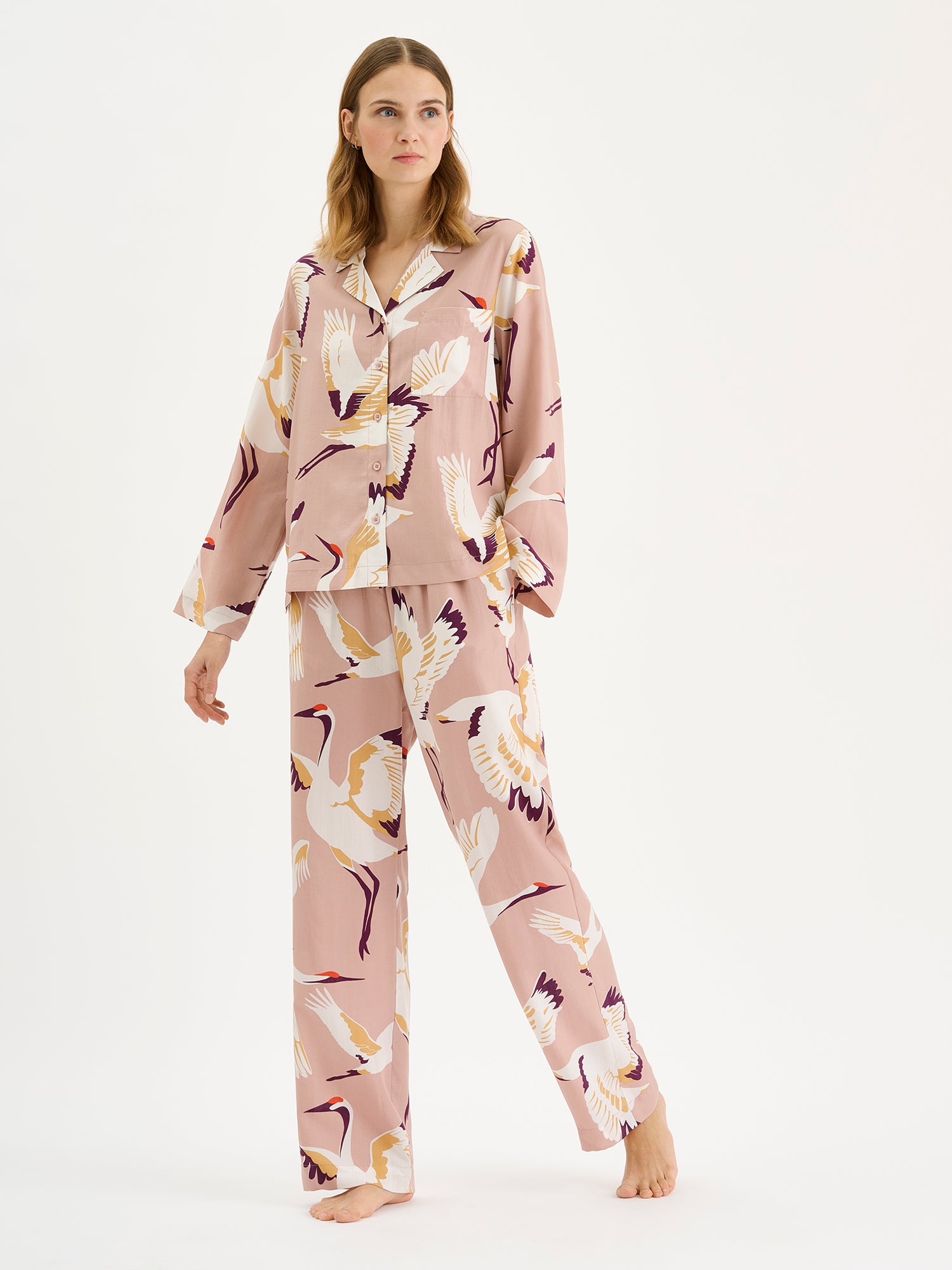 Women's comfortable Kurki pajama pants with an enchanting pale pink pattern, on a model paired with the matching pajama shirt.