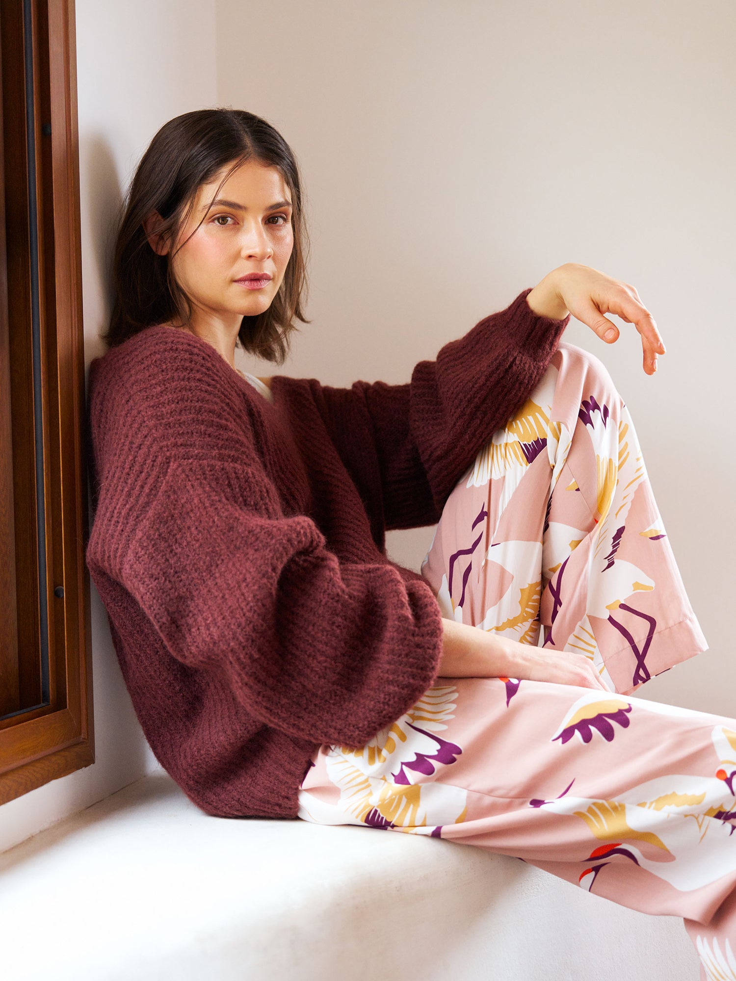 Women's comfortable Kurki pajama pants with an enchanting pale pink pattern, on a model paired with the karamelli knit sweater