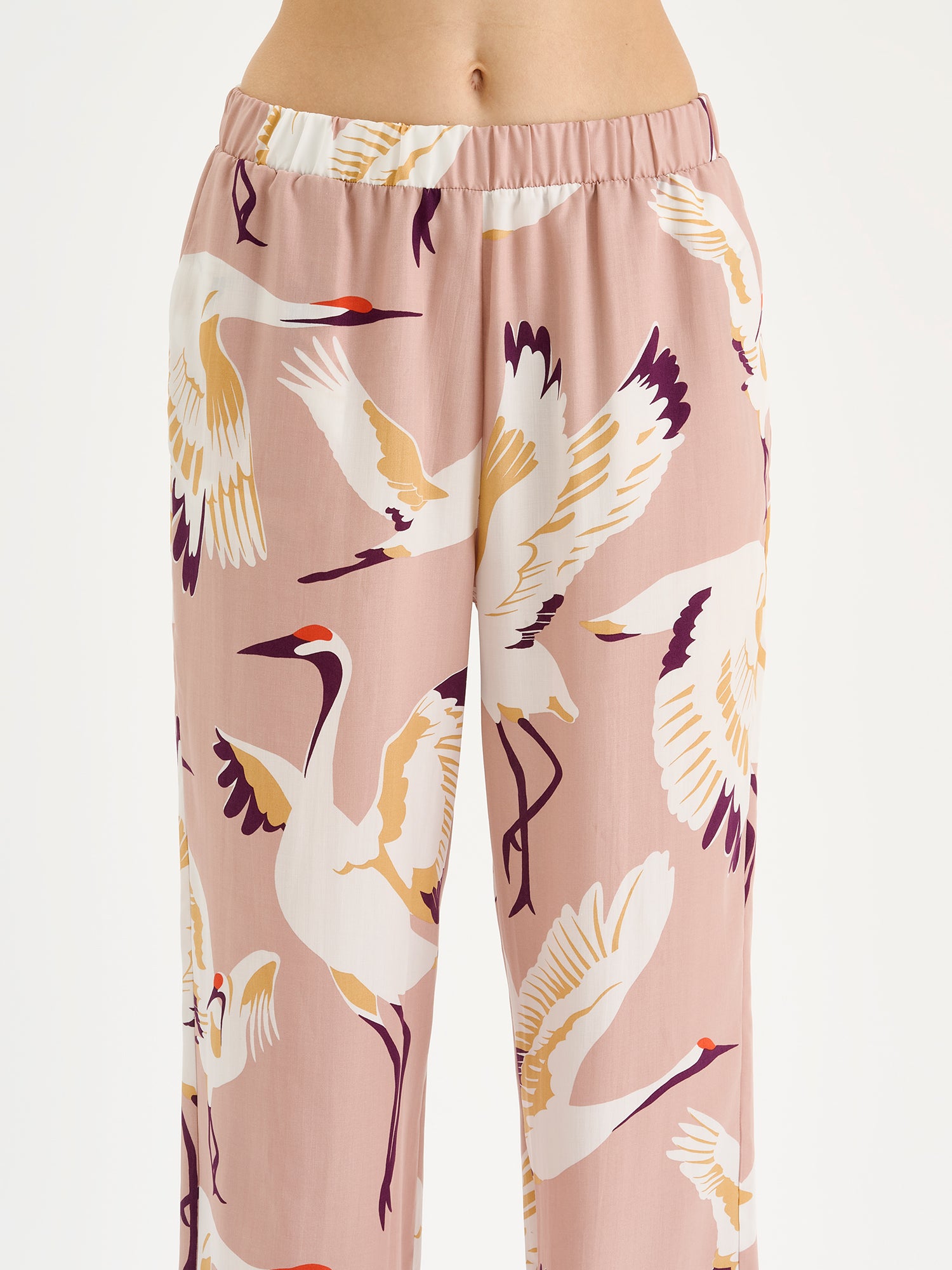 Women's comfortable Kurki pajama pants with an enchanting pale pink pattern, on a model close-up.