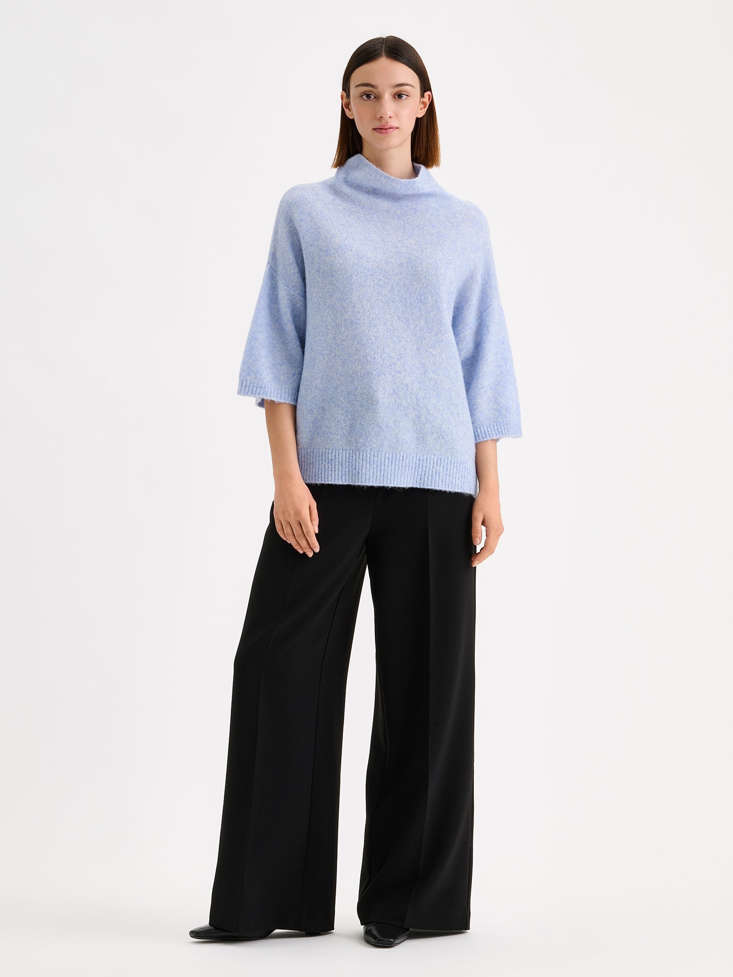 Nanso women's relaxed Alina knit sweater with a high neckline on a model with black trousers | S - 173m