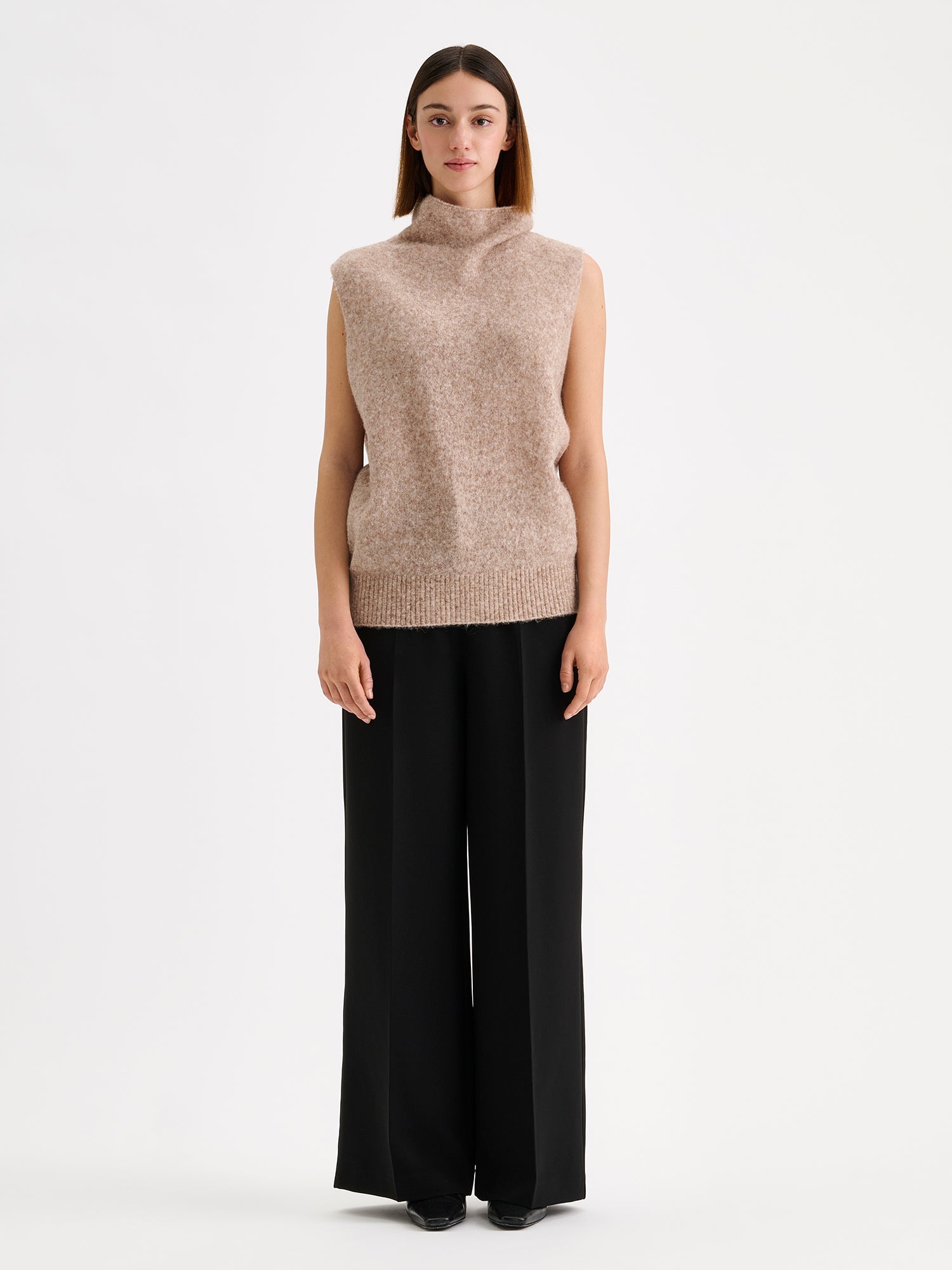 Nanso womens elegant and timeless wide-leg EEVA trousers in timeless black, on a model with a beige knitted vest. | 36 - 173cm