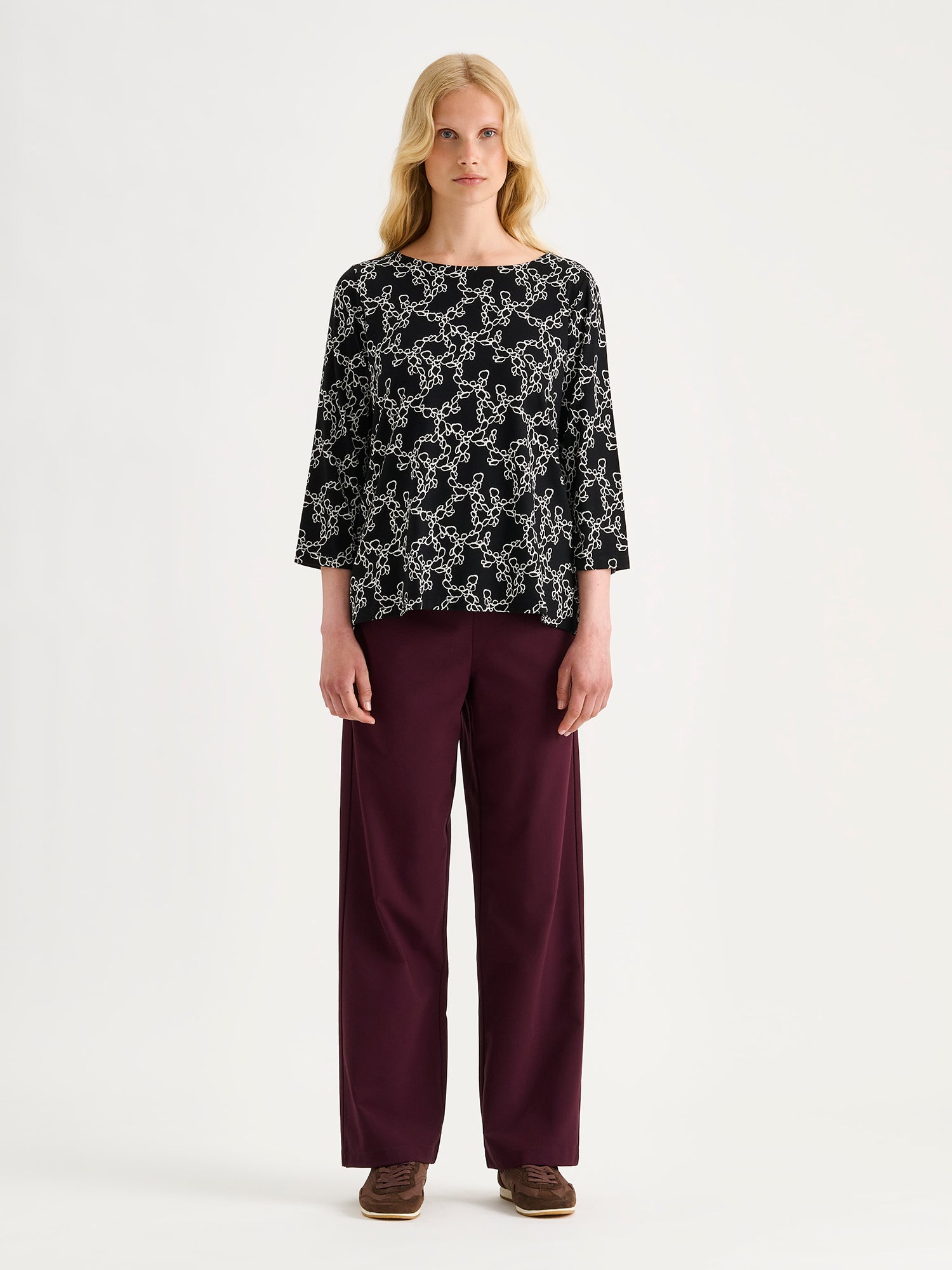 Women's patterned black and white Pieni Kide jersey blouse on a blonde model with winered trousers | S - 174cm