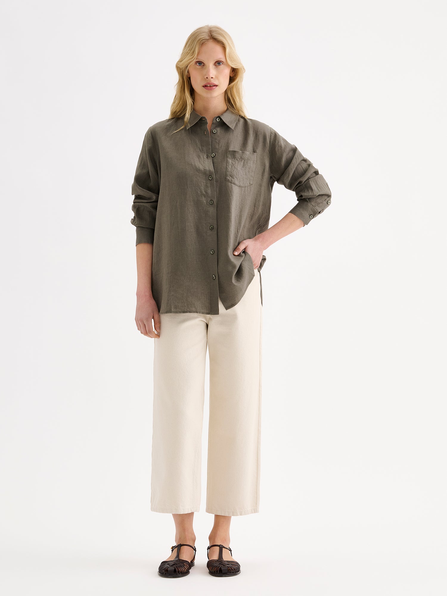 Nanso women's relaxed, classic and versatile olive green Lene linen shirt is crafted from woven linen fabric that is durable and breathable. The shirt features a front button closure and chest pocket and full-length sleeves. Pictured on a model 