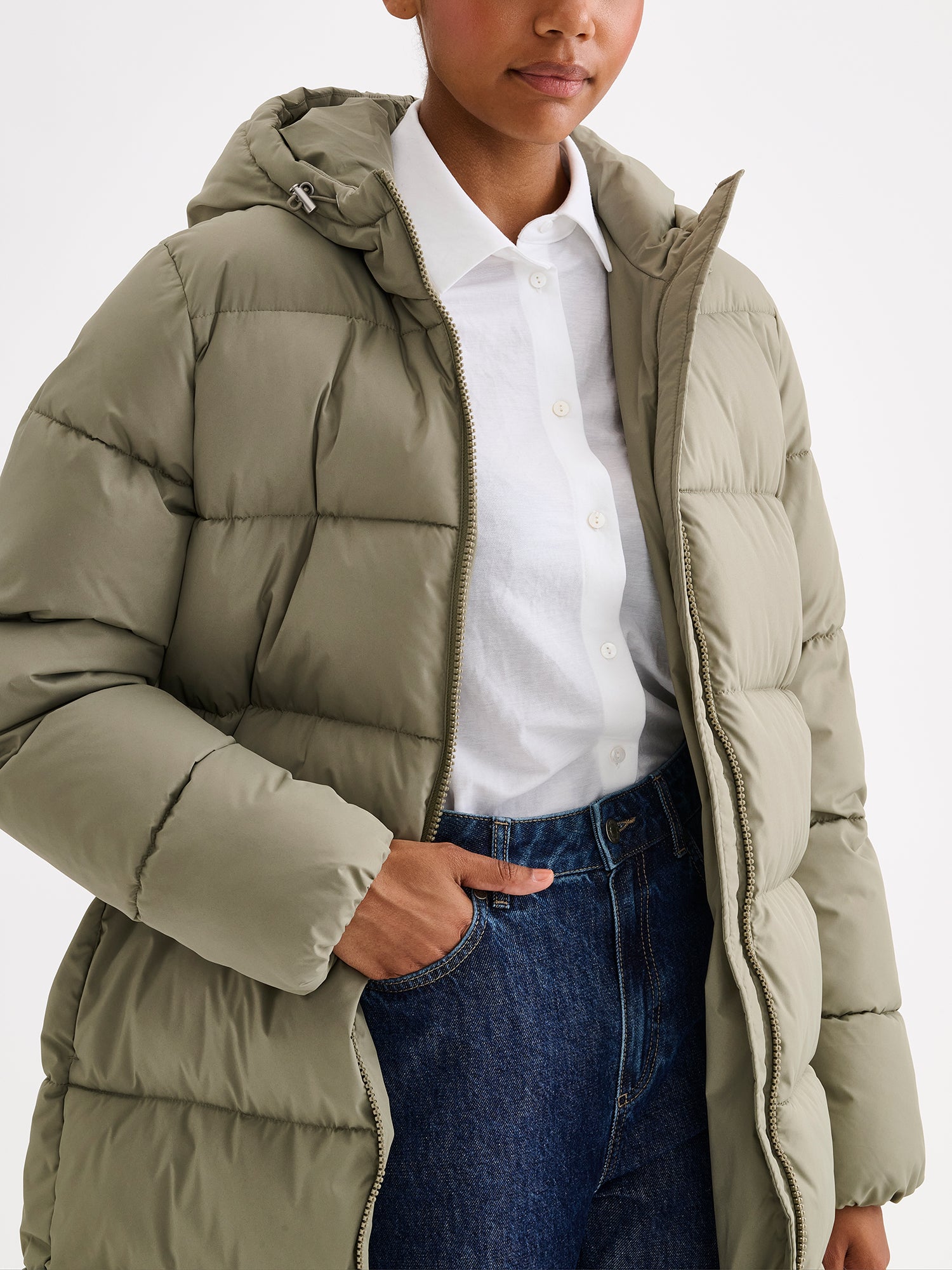 Nanso women's warm, padded yet pleasantly lightweight Lumi midi puffer coat on a model with jeans, close-up