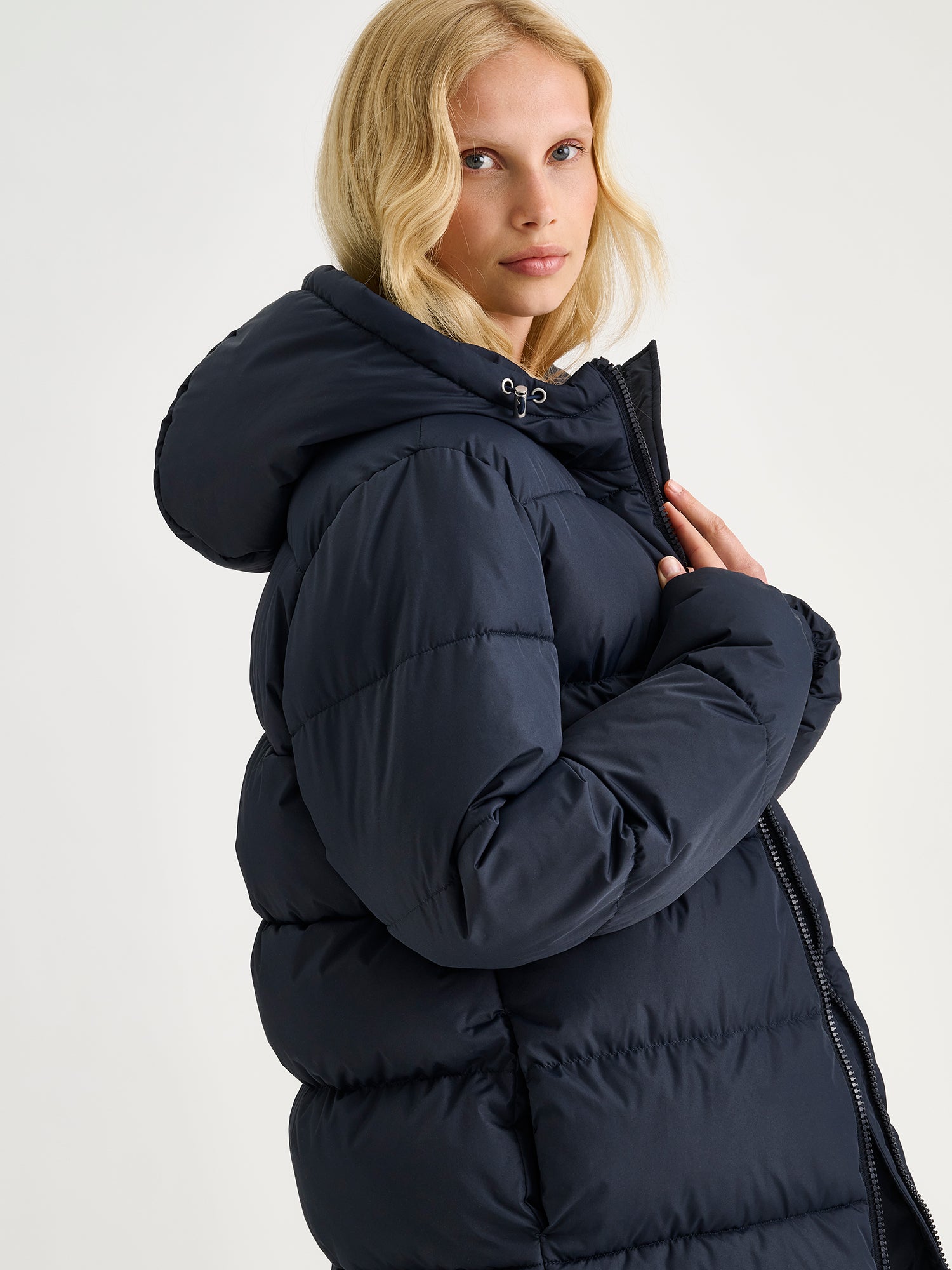 Nanso women's warm, padded yet pleasantly lightweight Lumi midi puffer coat in dark blue on a model, close-up