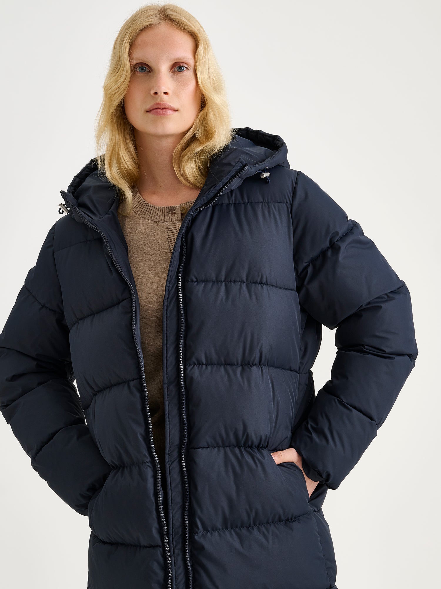 Nanso women's warm, padded yet pleasantly lightweight Lumi midi puffer coat in dark blue on a model, close-up