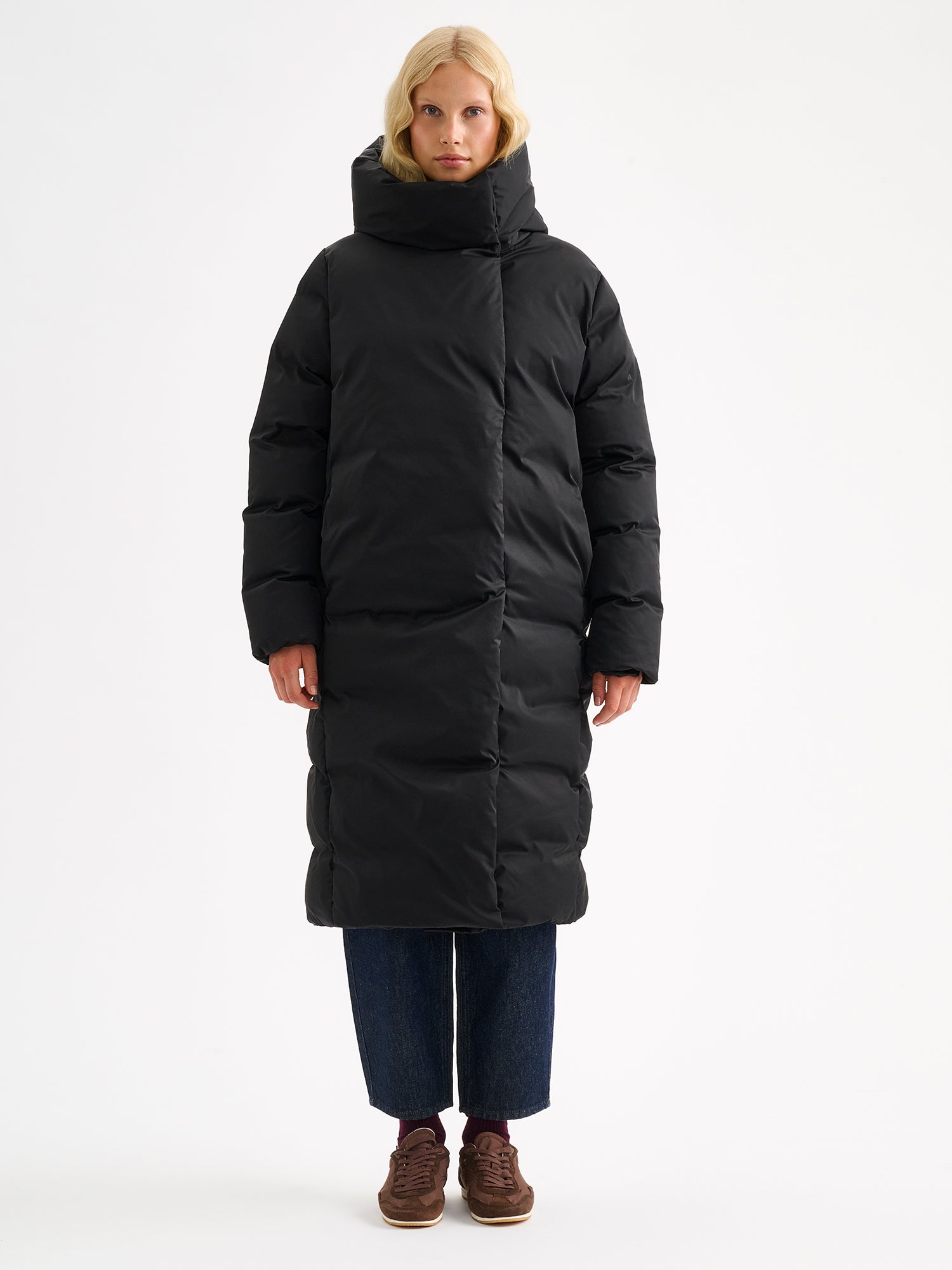 Warm and wonderfully voluminous, the long Inari puffer coat in black on a model.