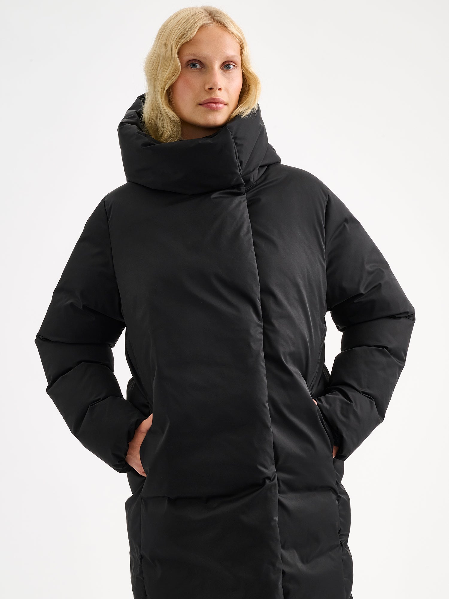 Warm and wonderfully voluminous, the long Inari puffer coat in black on a model.