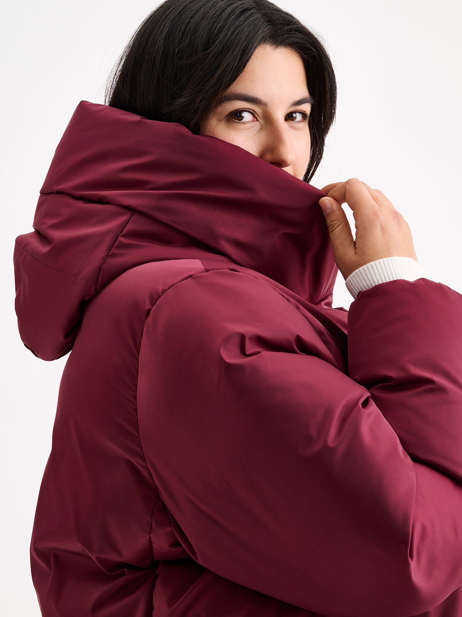 Warm and wonderfully voluminous, the long Inari puffer coat in winered on a model, close-up