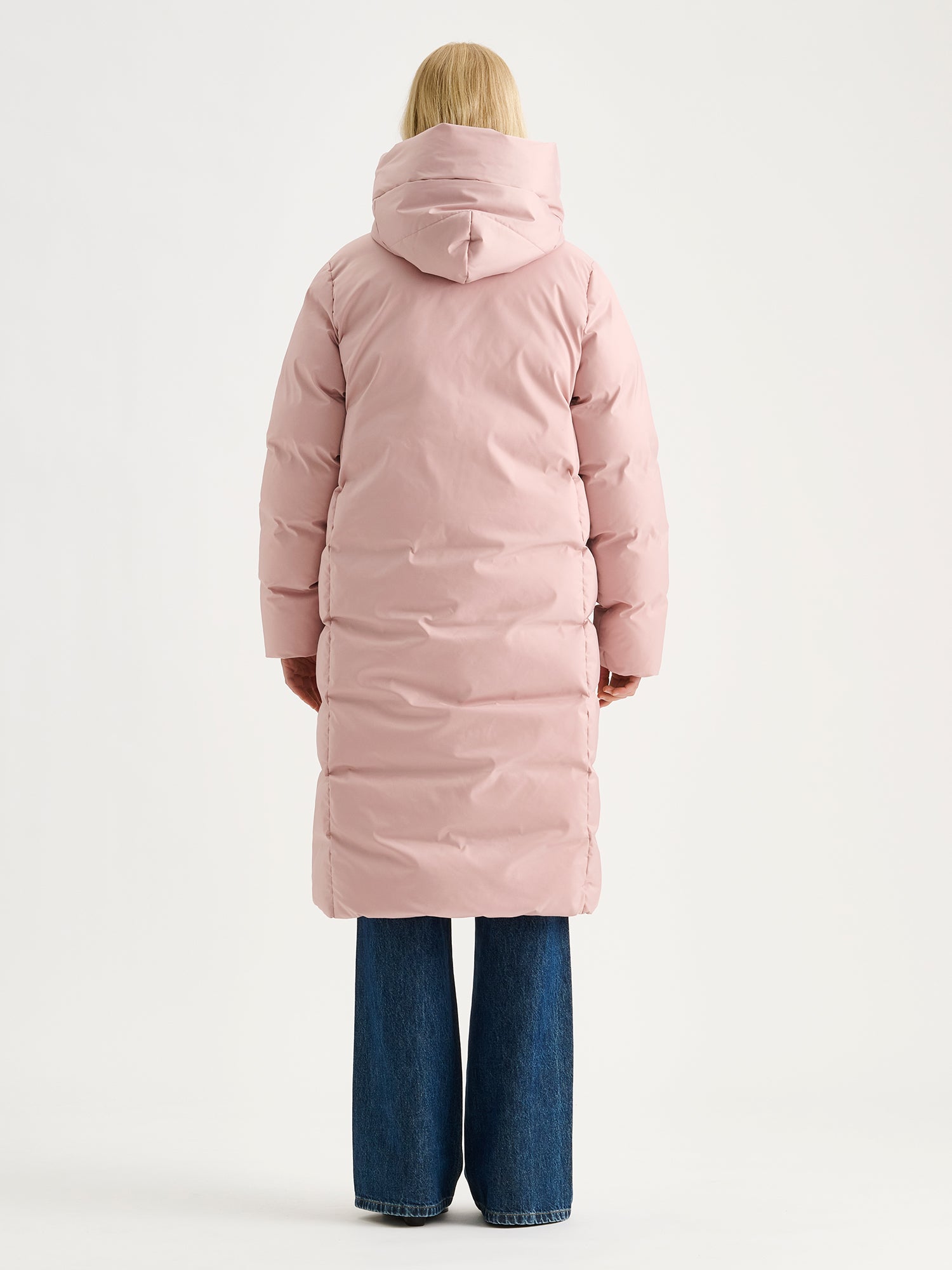 Warm and wonderfully voluminous, the long Inari puffer coat in light pink, on a model pictured from the backside