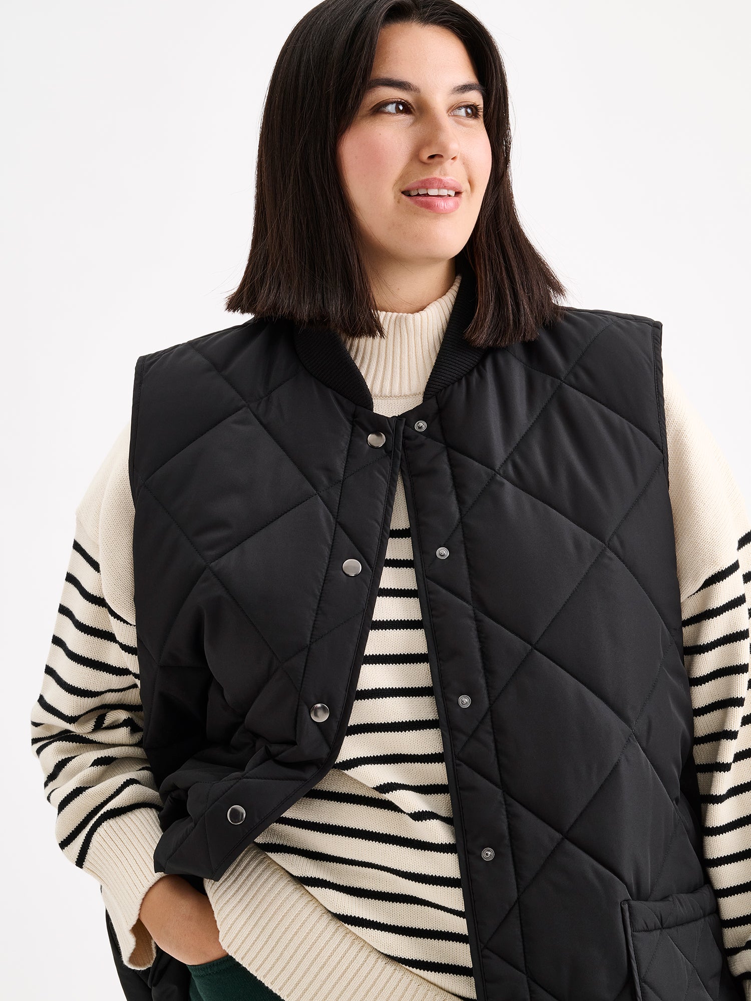 Nanso women's beautiful classic quilted vest in black, on a model with a striped sweater close-up.