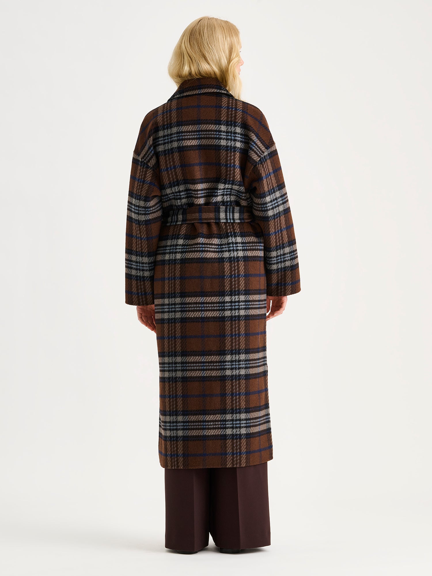 The stylish and timeless Astrid wool coat features a contemporary checked pattern, pictured on a model from the backside