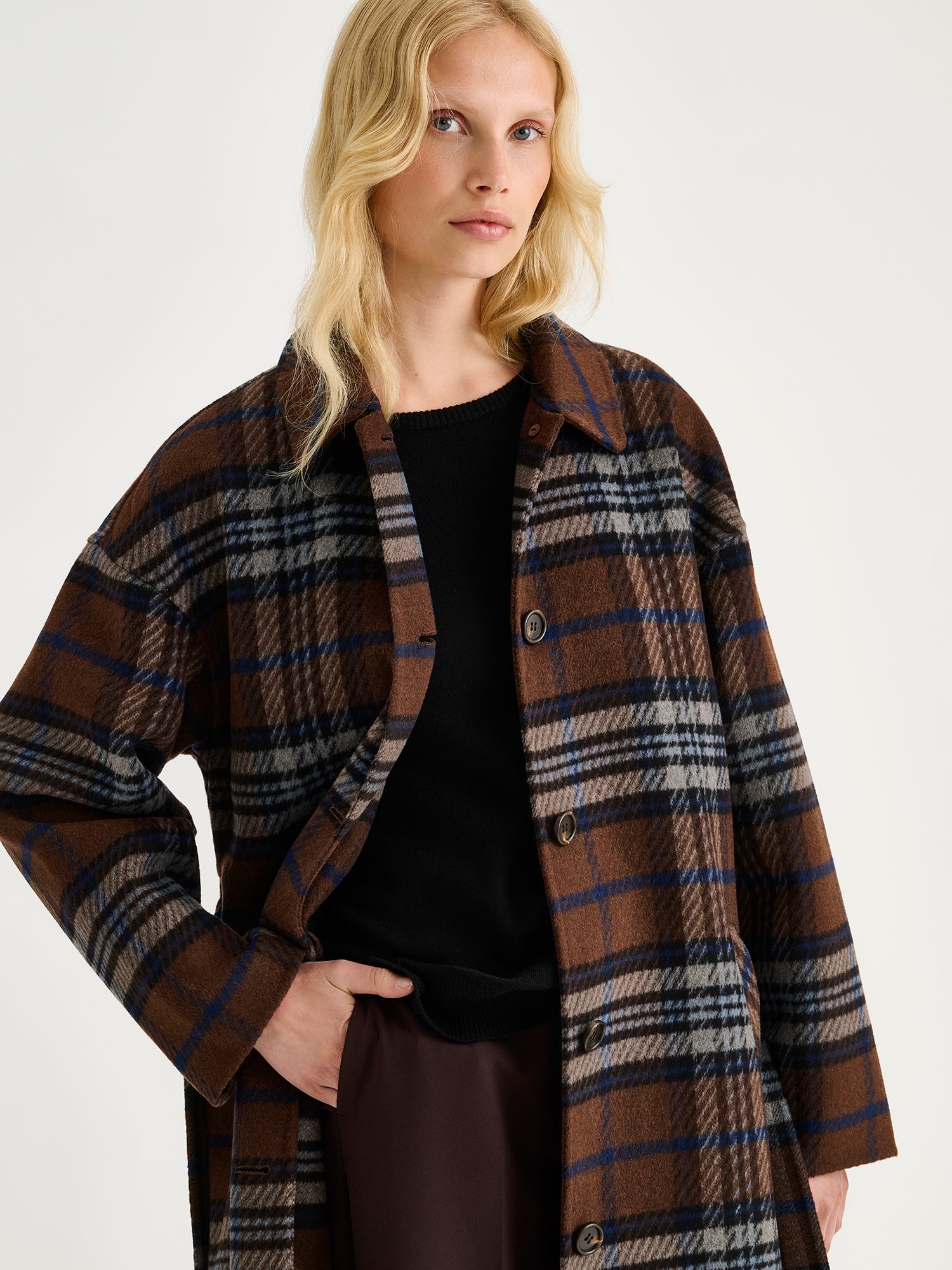 The stylish and timeless Astrid wool coat features a contemporary checked pattern, pictured on a model close-up